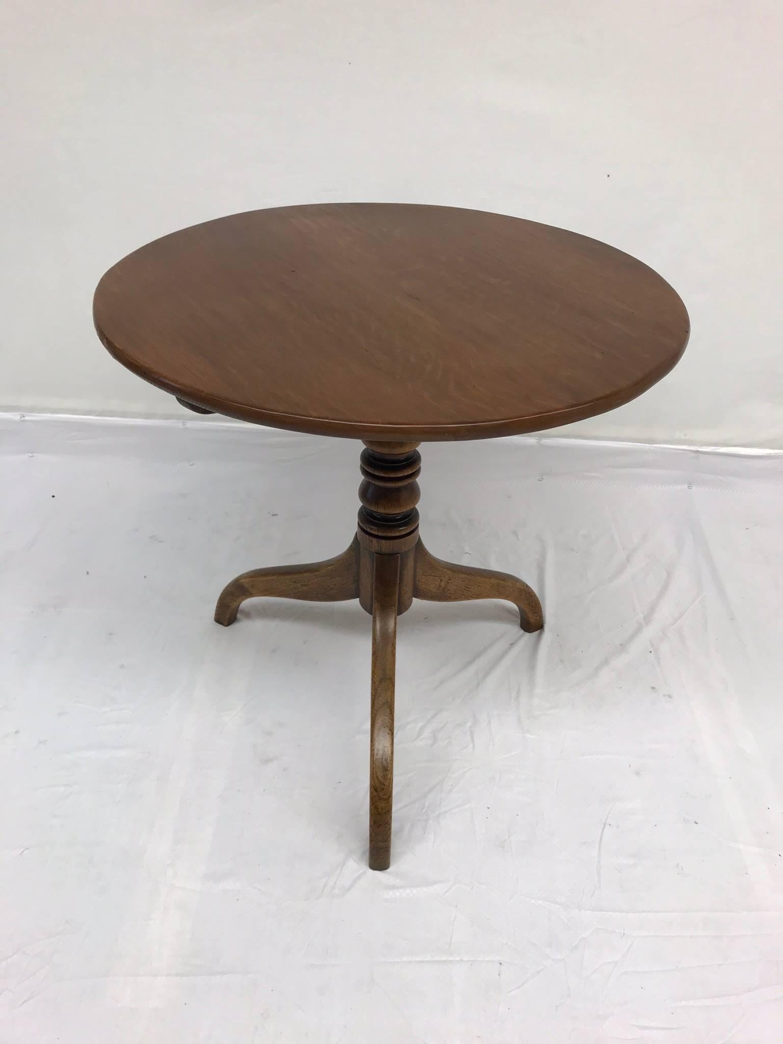 A charming 18th century Georgian round wood pedestal table with tripod legs and turned base. Place this next to a sofa and pile high with books and a great table lamp. Top flips vertically to place table flush against a wall. Hook under table to