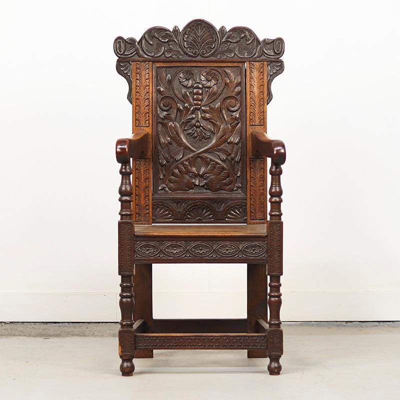 Ancien fauteuil anglais Wainscott en chêne foncé, datant du 18ème siècle. Une pièce d'histoire distinctive et décorative. Le dos est richement décoré et la patine est parfaite. Des signes d'usure minimes sont visibles, comme une petite garniture