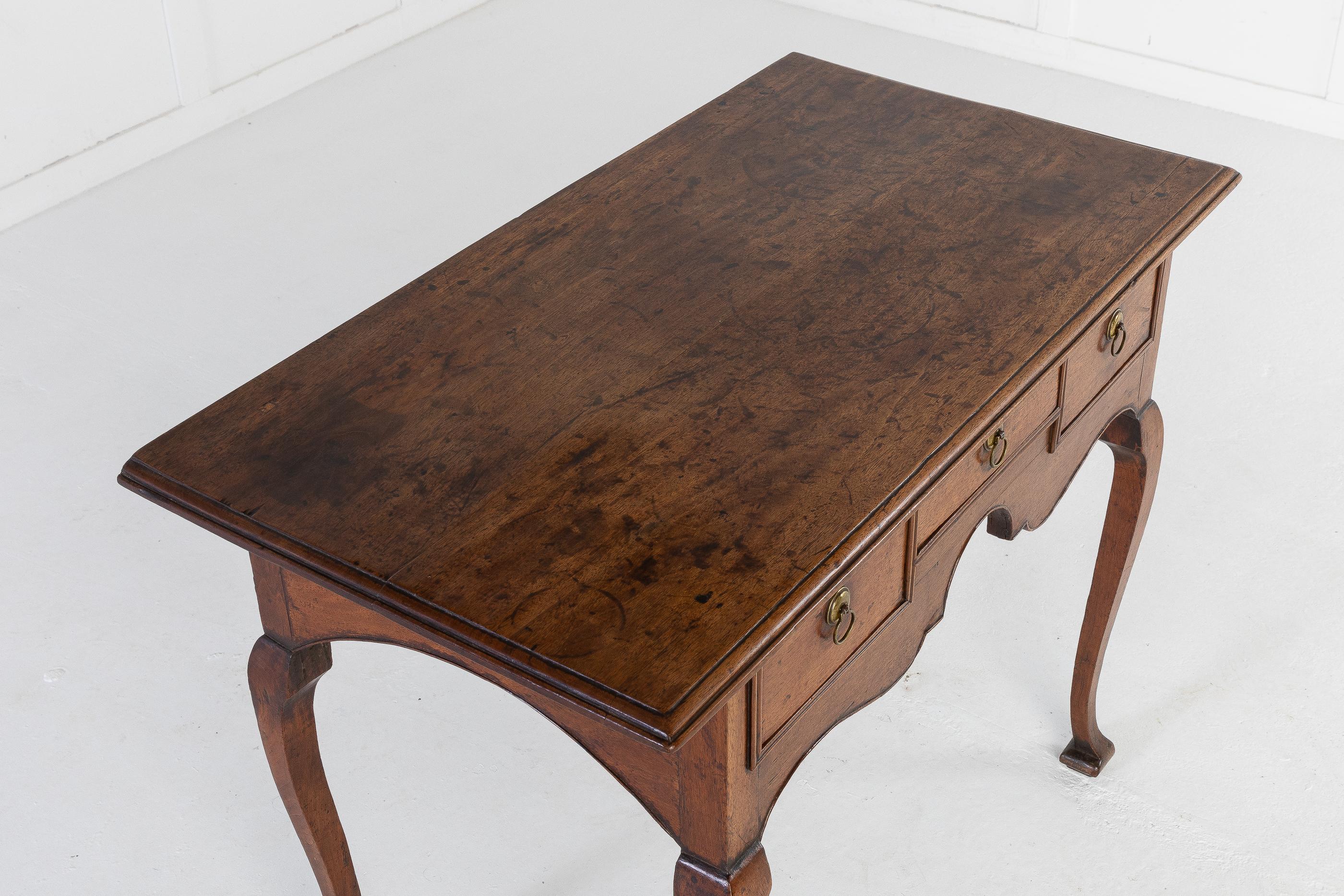 Elegant and fine model of an 18th Century, English walnut, country lowboy. With exaggerated moulded edge top, above three frieze drawers with small brass handles. Having a nicely shaped apron and raised on unusual, slender cabriole legs and small,