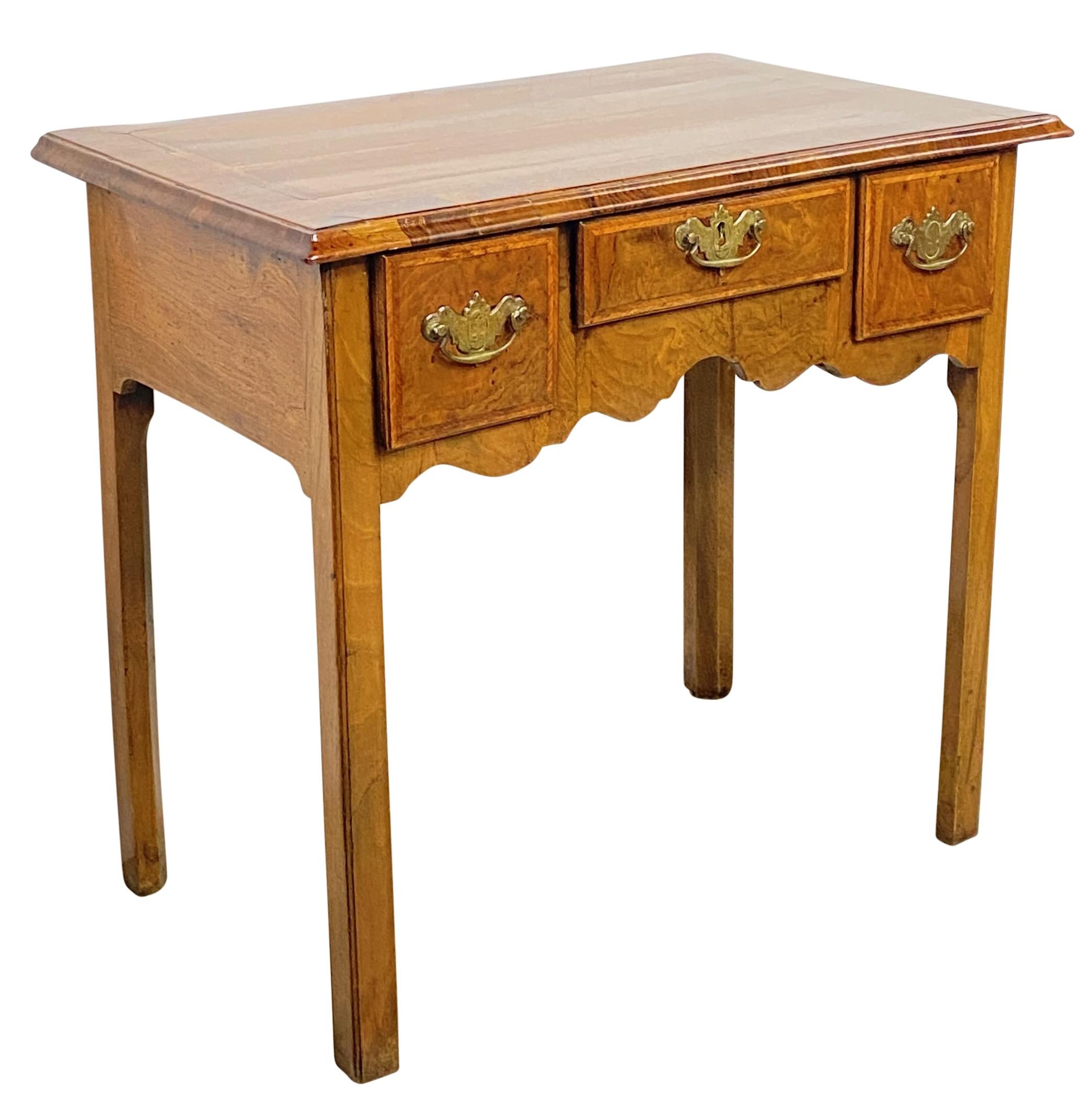 An attractive English walnut writing table or dressing table with brass hardware.
Solid walnut and walnut veneer over solid oak secondary wood. 
Having burl walnut drawer fronts with herringbone banding. 
In excellent antique condition.
England, mid