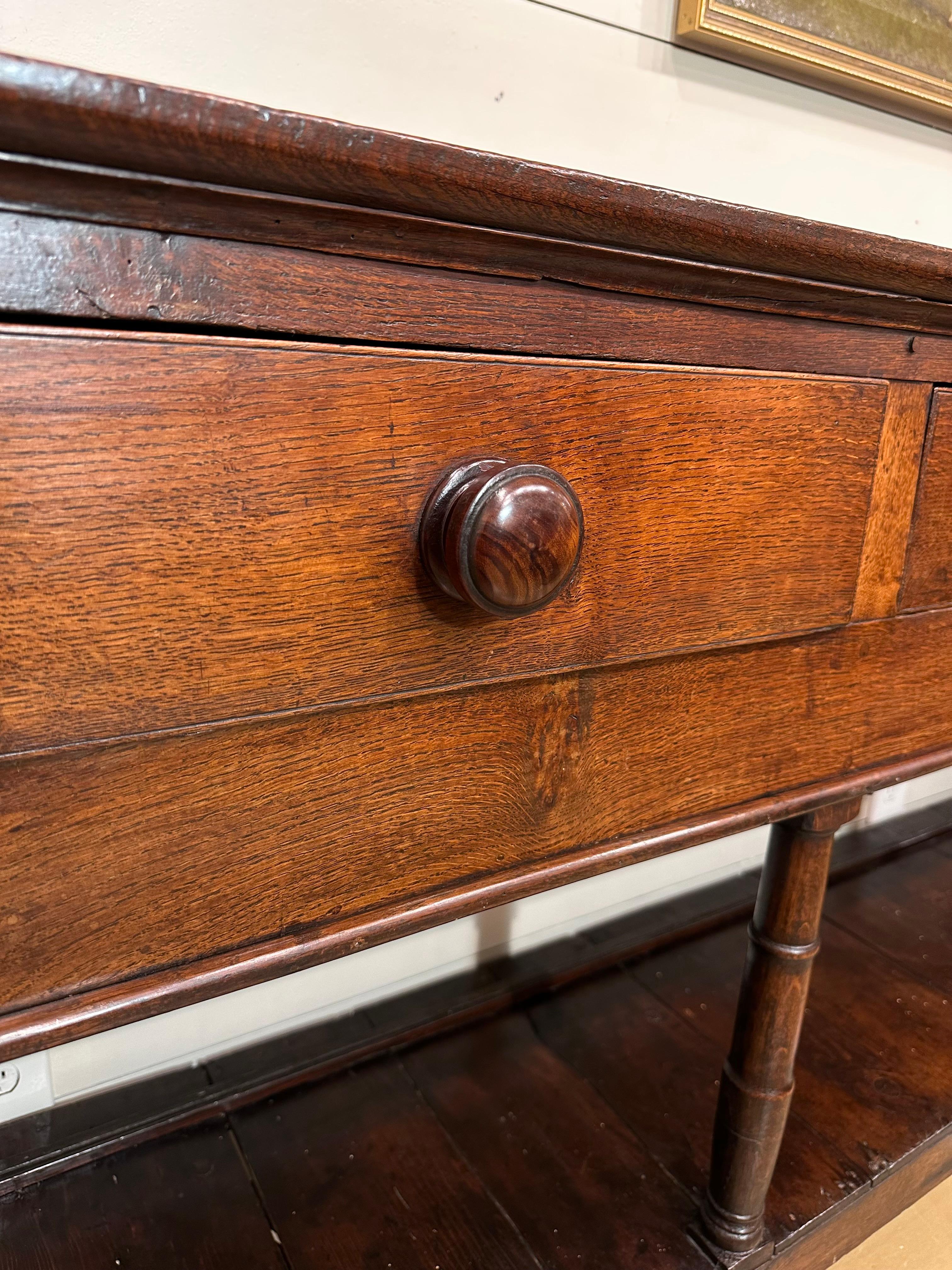 Own a piece of history with this 18th Century English Welsh Dresser Base. Crafted with timeless charm, this antique dresser exudes rustic simplicity. The sturdy wooden construction and warm patina tell a story of centuries gone by. With its
