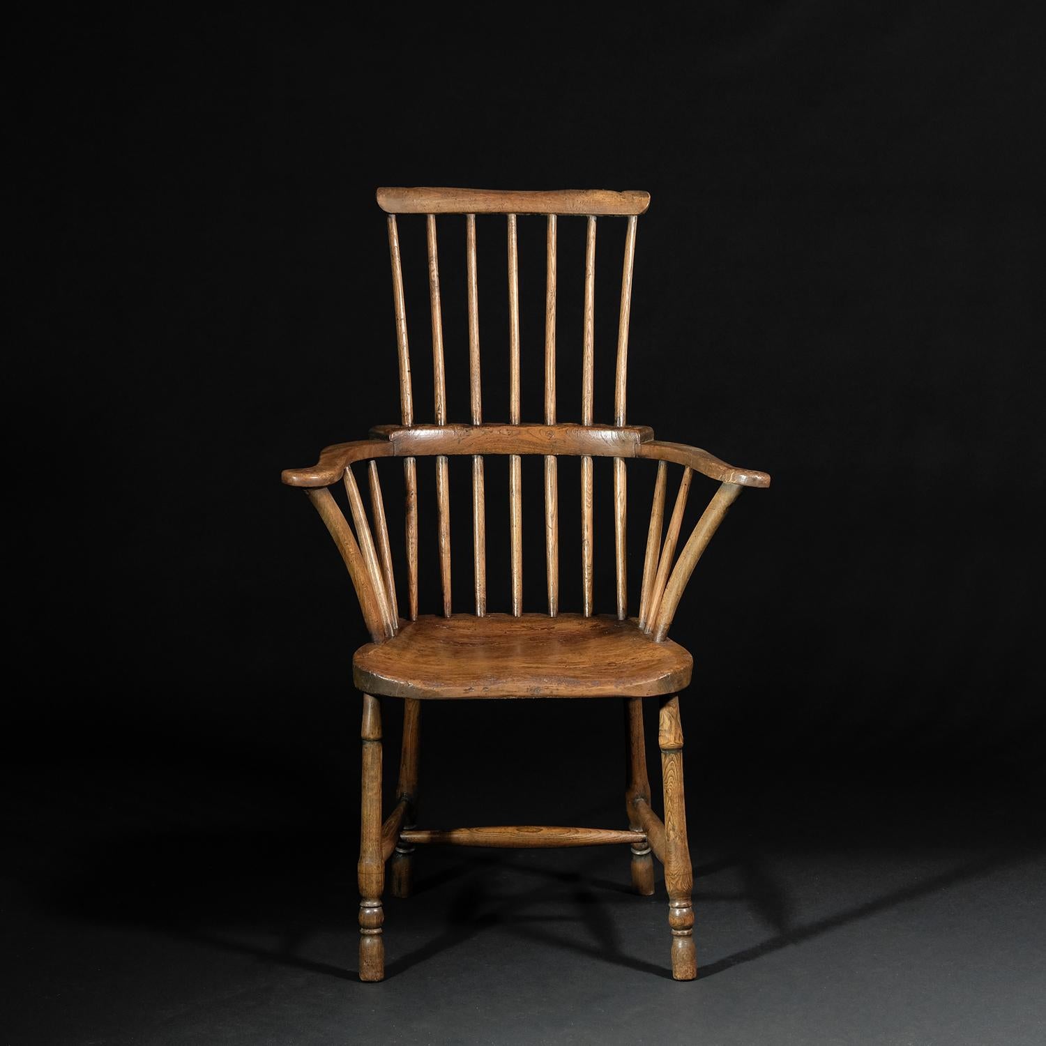 A simple comb back Windsor armchair; a little more primitive from the norm. All legs with egg and reel turnings and hoof feet. Saddle shaped seat with crooked arm supports and four underarm spindles. The outswept three-part arm with long hand drawn