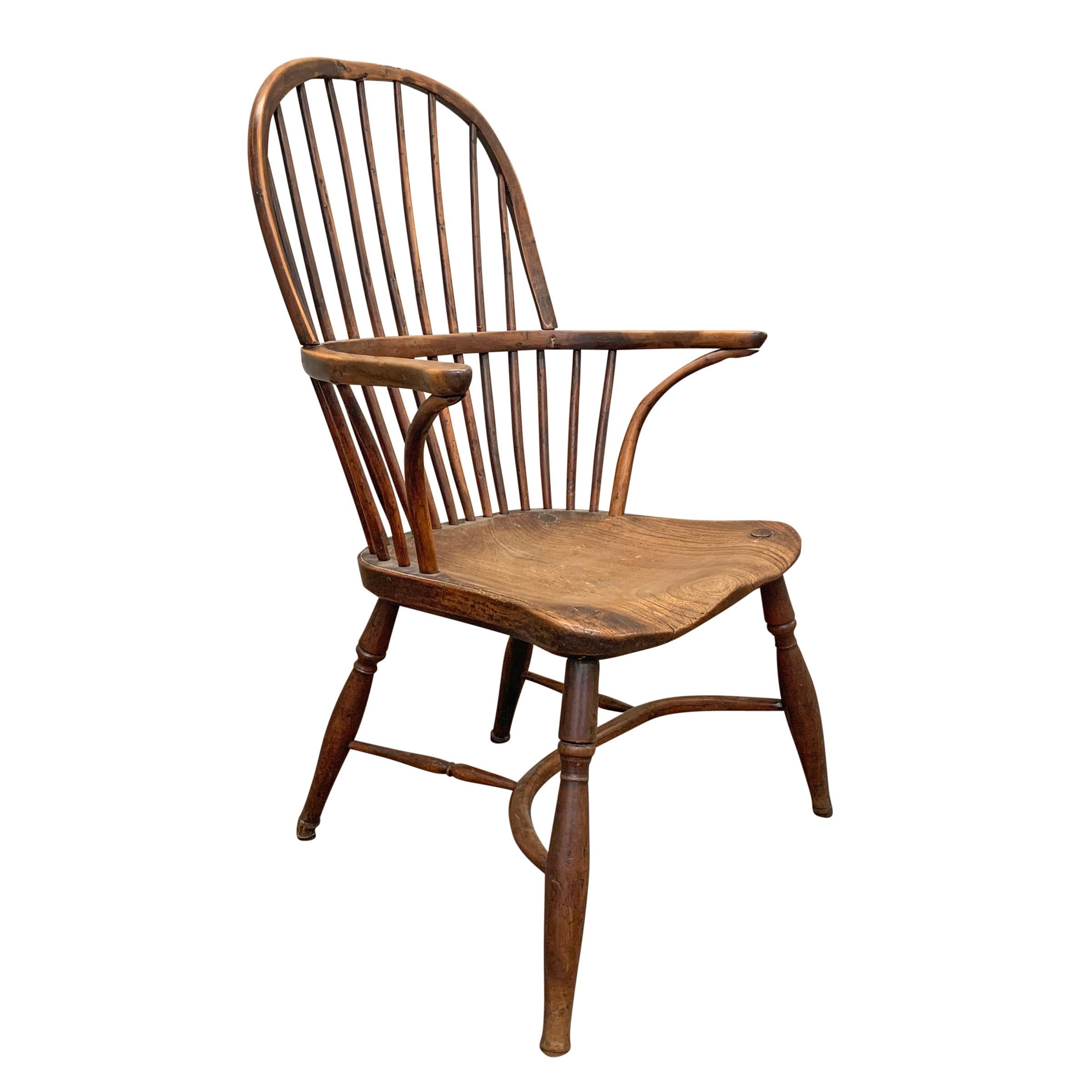 A wonderful late 18th century English elm and yew wood Windsor chair with a hoop back, out-turned arms supported by inverted stretchers, turned legs connected by a bentwood stretcher. The seat is one piece of wood with a beautiful patina.