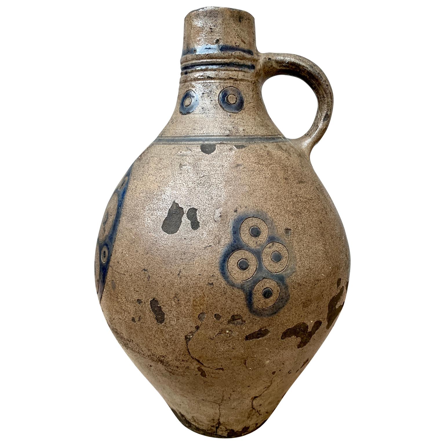 An 18th century European ceramic pitcher, most probably from Germany, with glazed decoration in blue colour representing flowers on a beige background. It has most probably been used for serving wine.