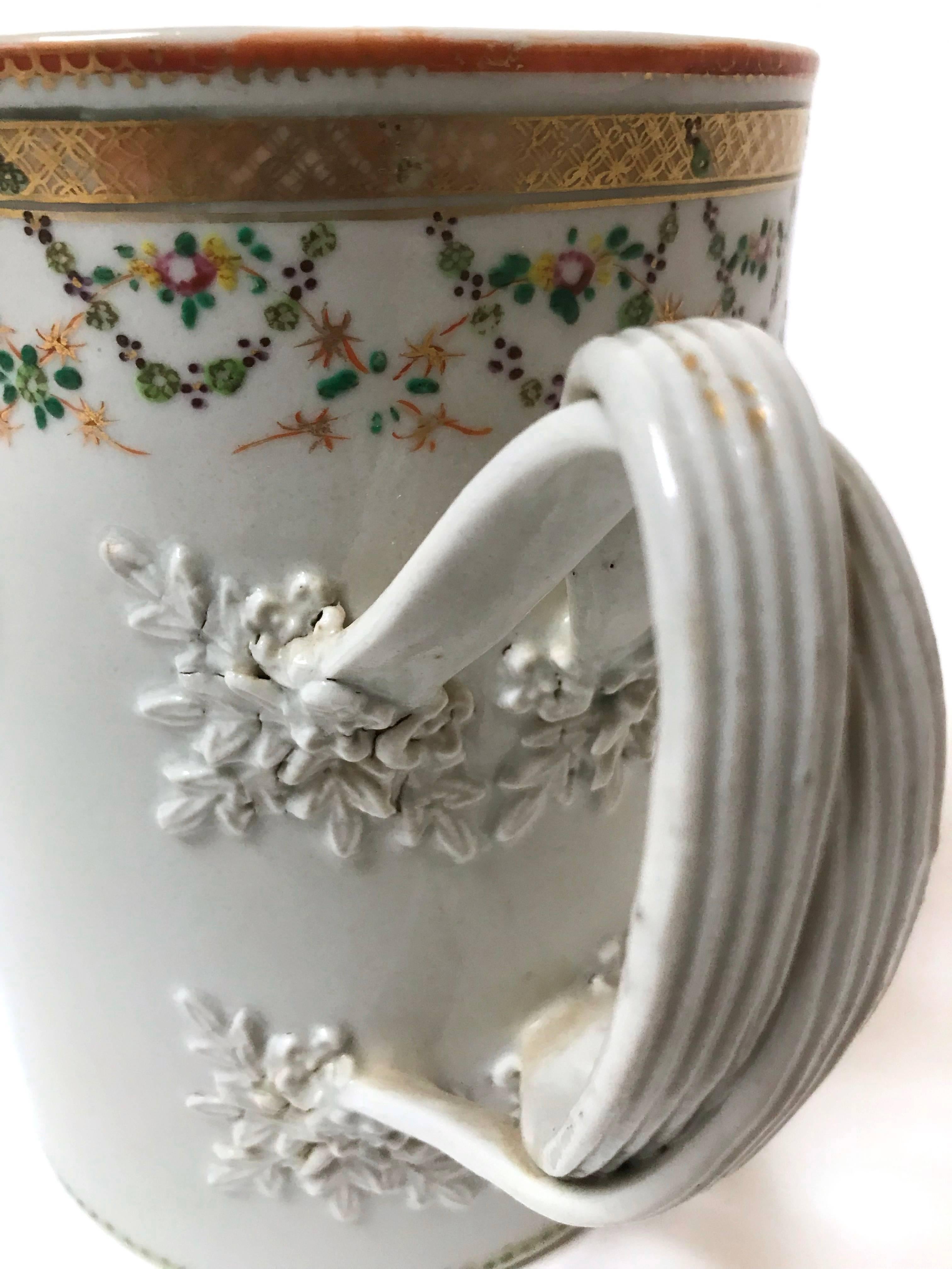 A rare large cylindrical Chinese export porcelain tankard, sometimes referred to as a toasting cup, dating to the late 1700s, with applied twisted and reeded, double-strap handles and high relief carved floral and foliate terminals, over-glaze