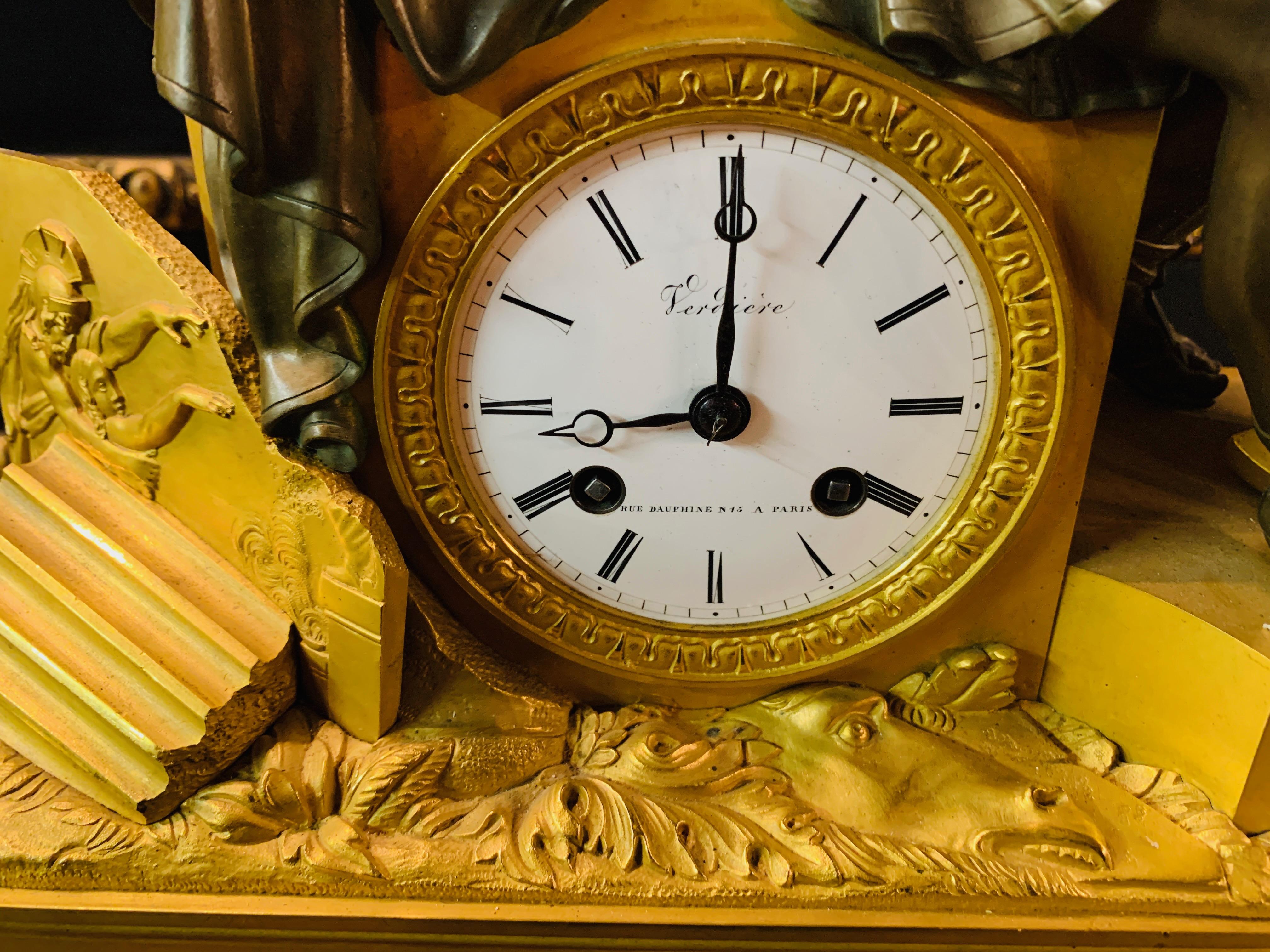 Empire figure mantel clock fire-gilded, Paris around 1790, Roman seat on a base with ornaments and rocailles, helmet and warriors decorated, white enamel dial with Roman numerals and minute track, blackened hands, French. Roundwork with 1/2 hour