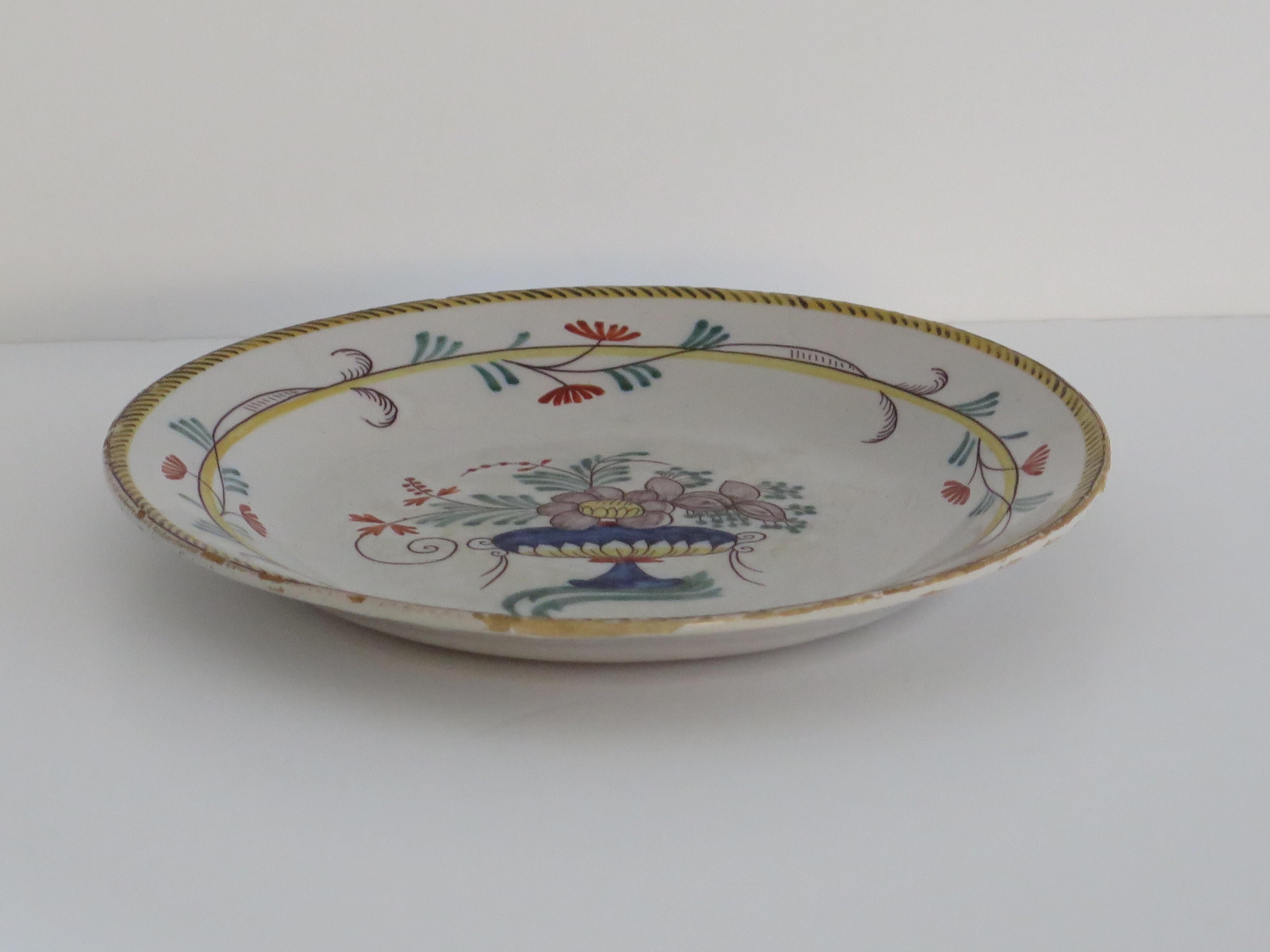 This is a very decorative French Faience plate dinner plate made from tin-glazed earthenware (pottery) which we date to the late 18th century.

The plate has a pan shaped base with no foot rim.

This plate is hand-painted in a flowing style with
