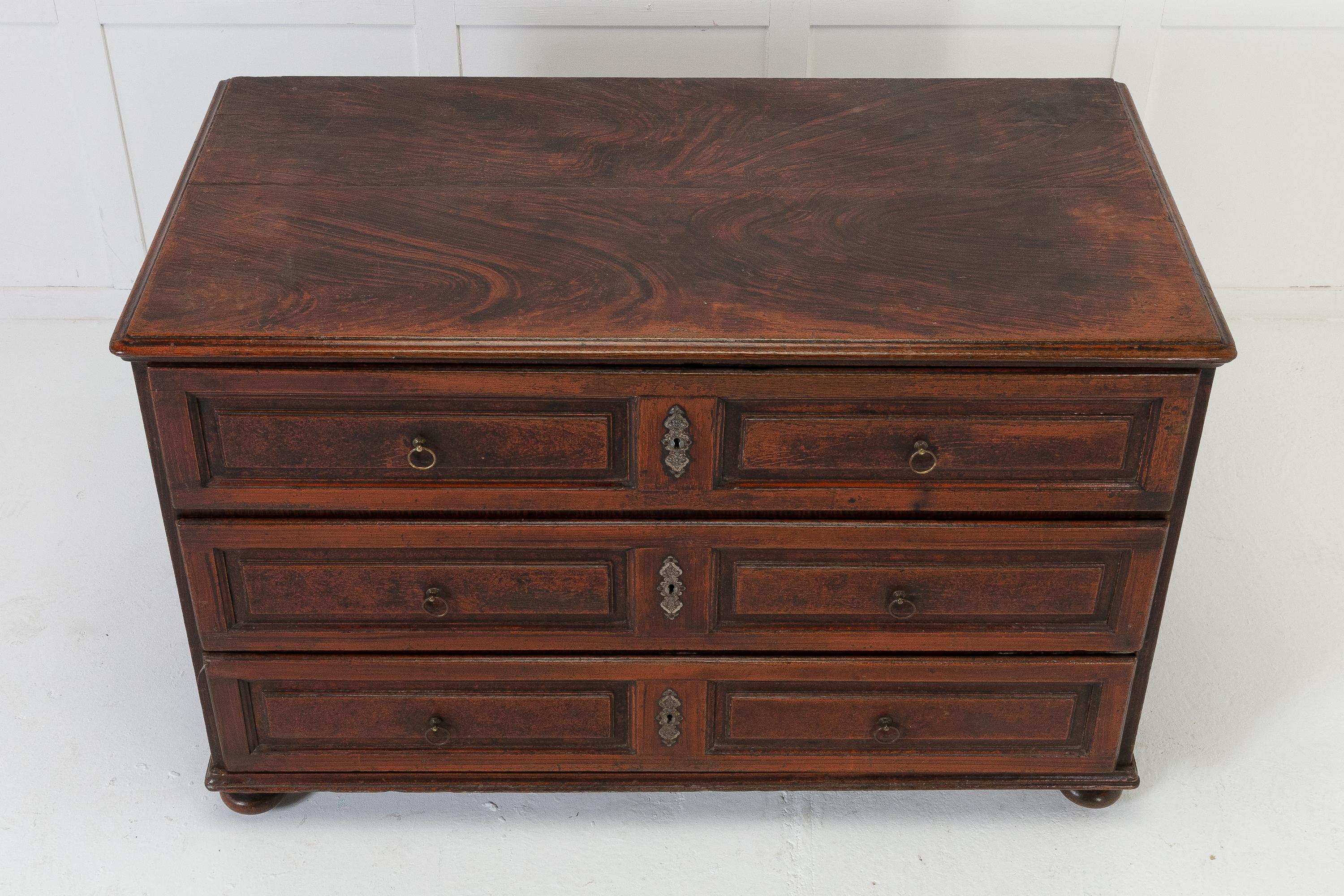18th century three drawer commode with its original faux wood paint. The drawer fronts are finished with panels, original ring pull handles and escutcheons. The sides are panelled and it stands on squashed bun feet at the front and square tapering