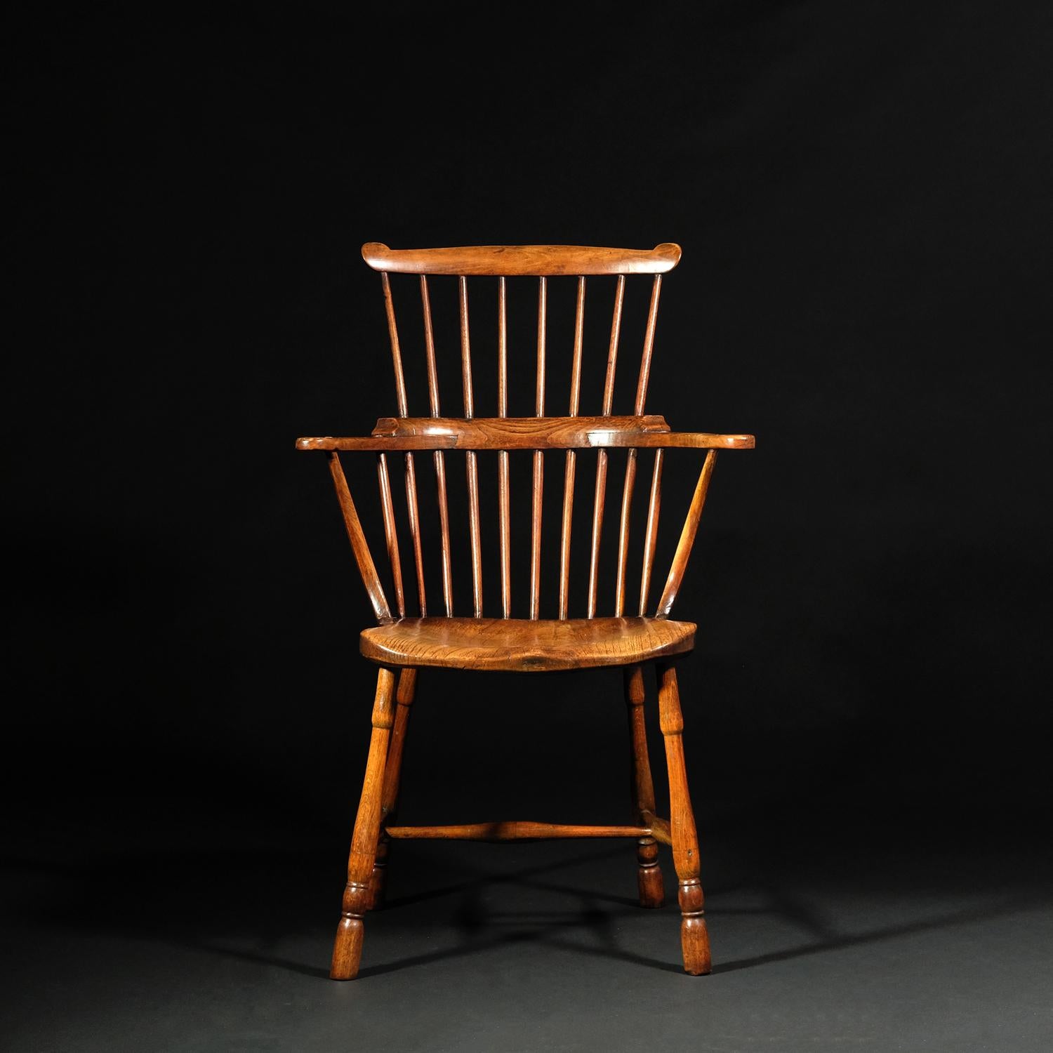 A fruitwood comb back Windsor chair, sometimes referred to as a Goldsmith chair as it bears a resemblance to the chair once owned by 18th Century author, Oliver Goldsmith, now in the V&A. Egg and reel turned legs, both front and rear, united by a