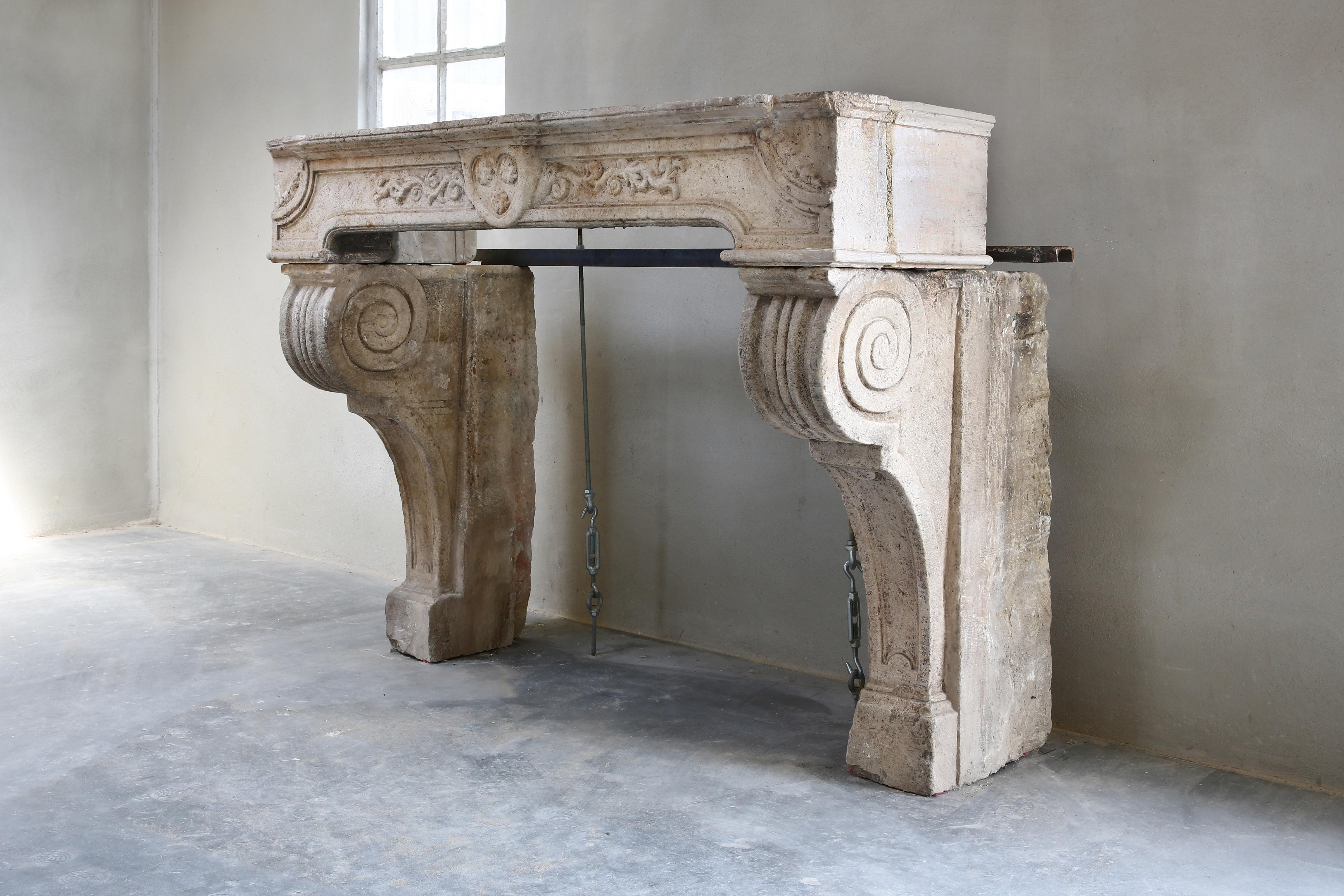 Antique French limestone fireplace from the 18th century, from the time of the Renaissance. This beautiful fireplace is more than 200 years old and is richly decorated with various ornaments and lines. The fireplace has a beautiful molding and is