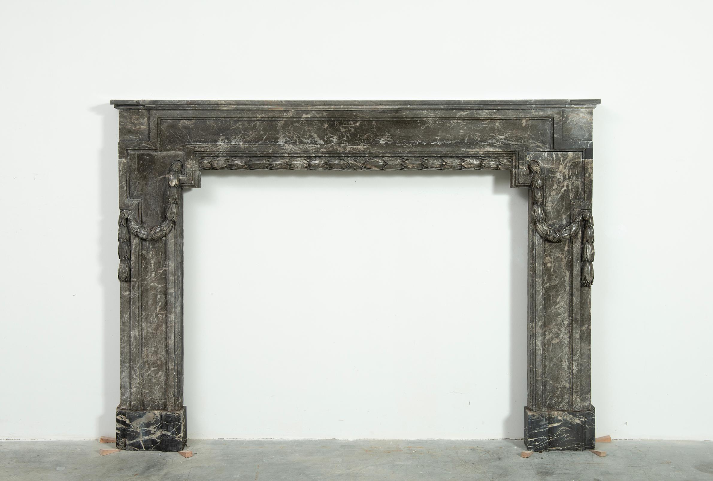 Strong 18th century fireplace mantel in Gris d'Ardenne marble.

This monumental antique French fireplace is beautifully decorated with profiled paneling combined with a draped laurel leaves and berries garland from left to right.
Especially nice