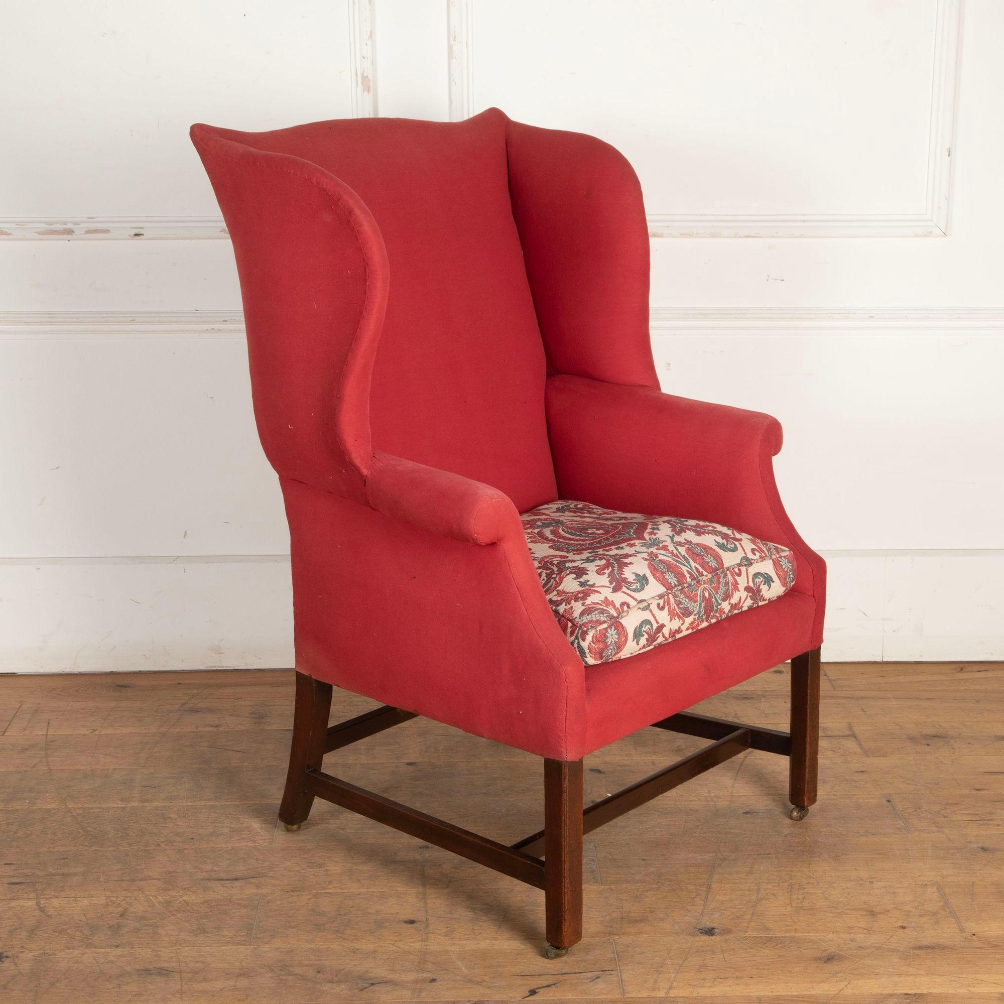 Fauteuil à oreilles du XVIIIe siècle Ce beau fauteuil a des proportions généreuses avec des ailes prononcées. La chaise est posée sur des pieds carrés en acajou avec des brancards traditionnels qui se terminent par des roulettes en laiton d'origine.