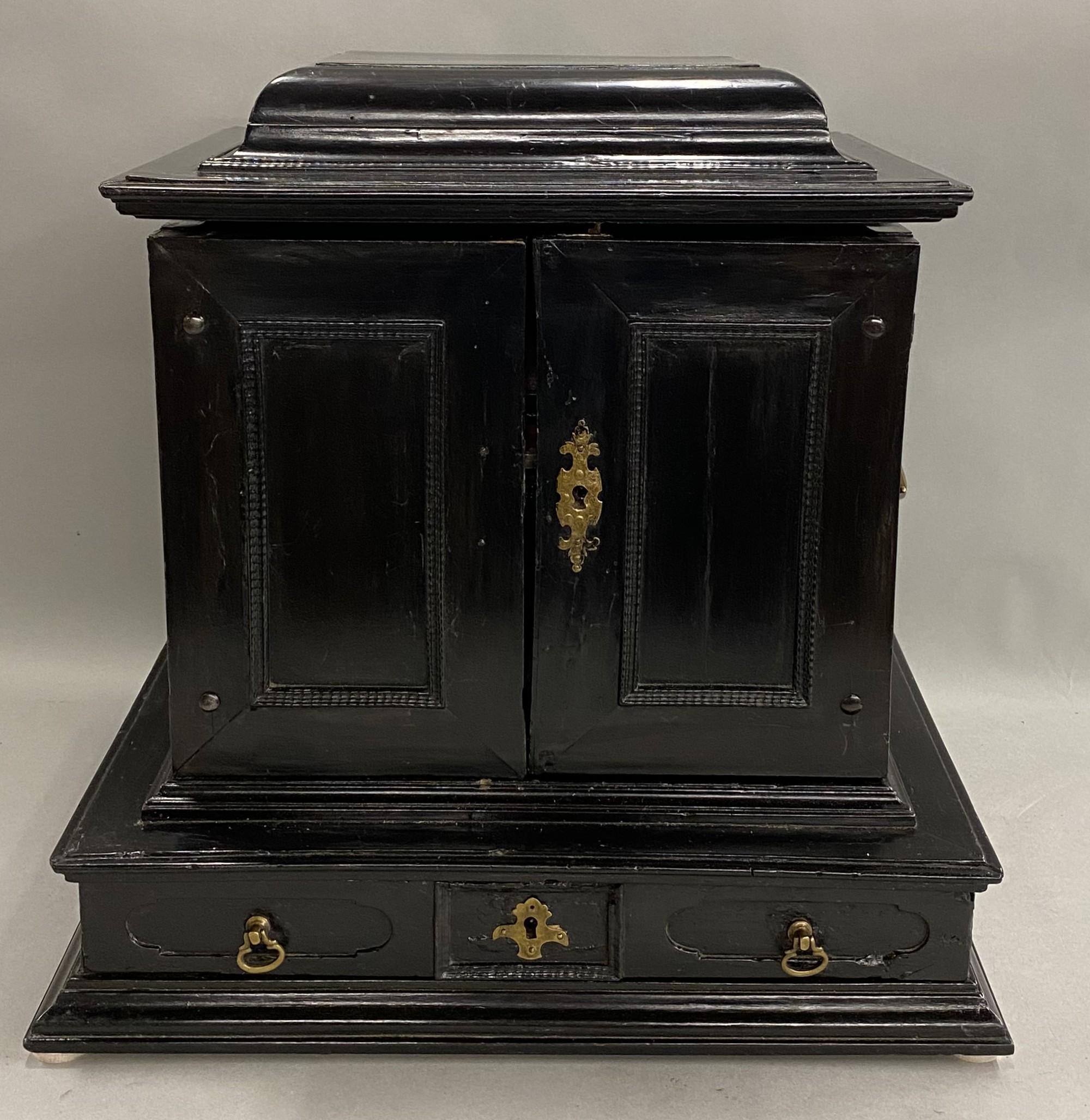 Un raffinato esempio di mobile da collezione fiammingo ebanizzato del XVIII secolo con piano di chiusura a cerniera e due ante frontali con rivestimento interno in finto guscio di tartaruga rossa, che si aprono su un'area di stoccaggio a scomparti
