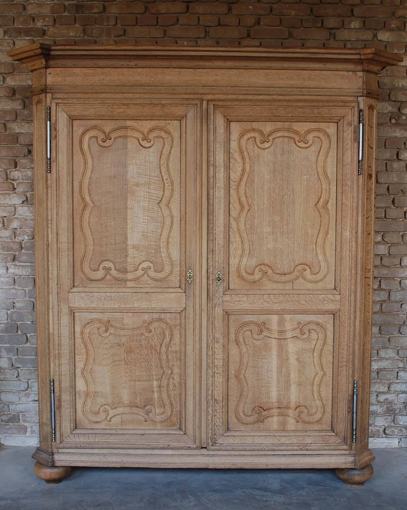 A beautiful Belgian two-door cabinet in Louis XIV style and made in solid oak.
The cabinet has fine carved curly brackets or accolades surrounding the raised panels in the doors.
It has a typical cornice and the cabinet stands on solid bun