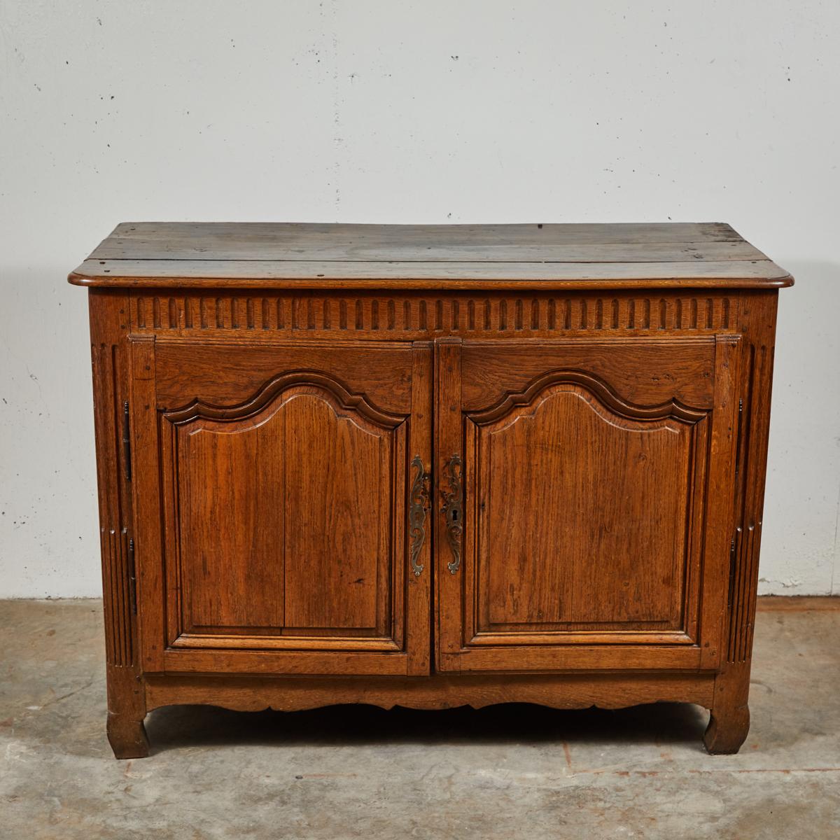 18th century Flemish provincial oak buffet with fluted carving, panel doors, and a carved apron base. Features a highly ornamented metal keyhole. 