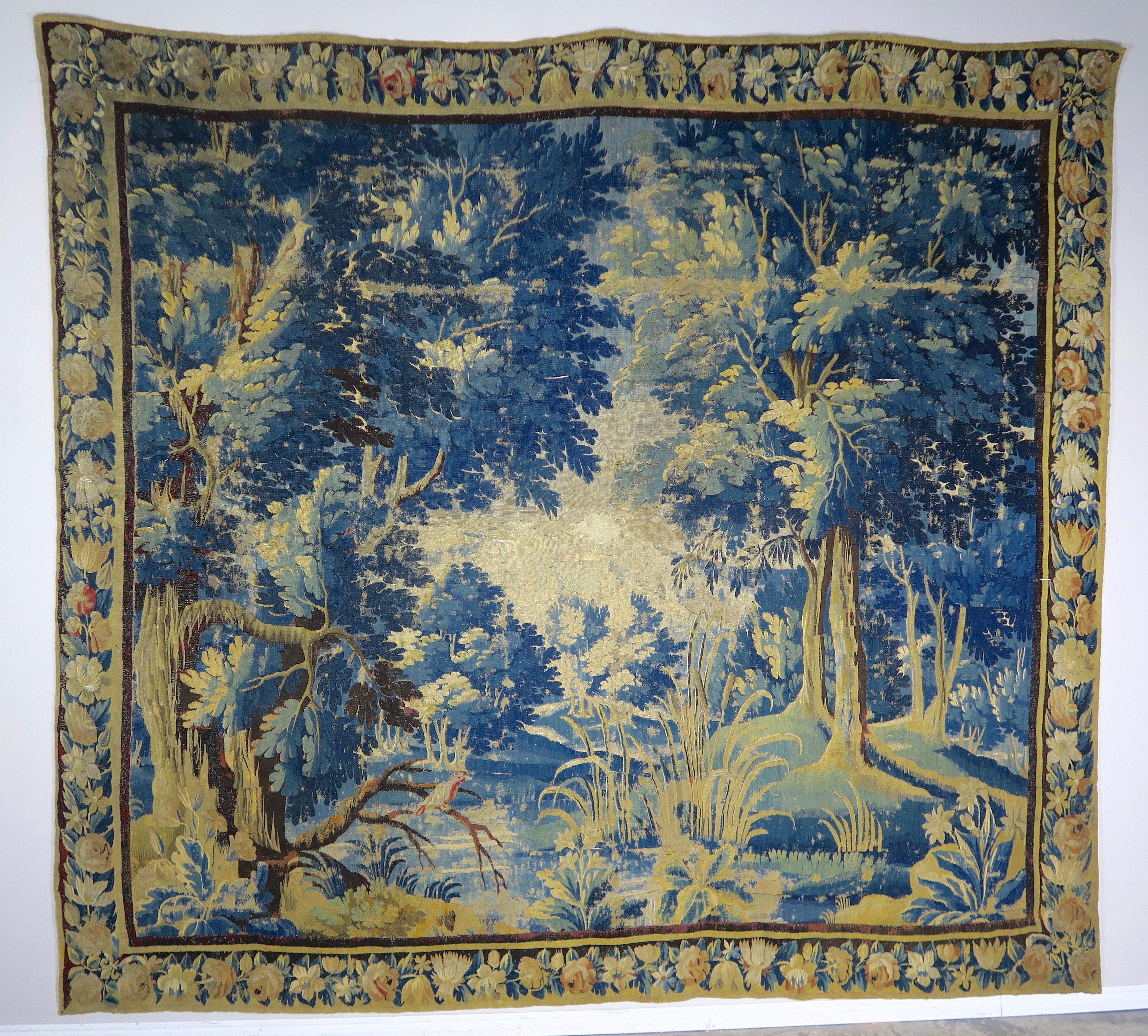 18th century Flemish Verdure tapestry depicting birds and a beautiful scene of foliage and trees throughout. The tapestry is handmade in both silk and wool with vibrant hues of greens, blues, gold and more. Good overall condition with areas of