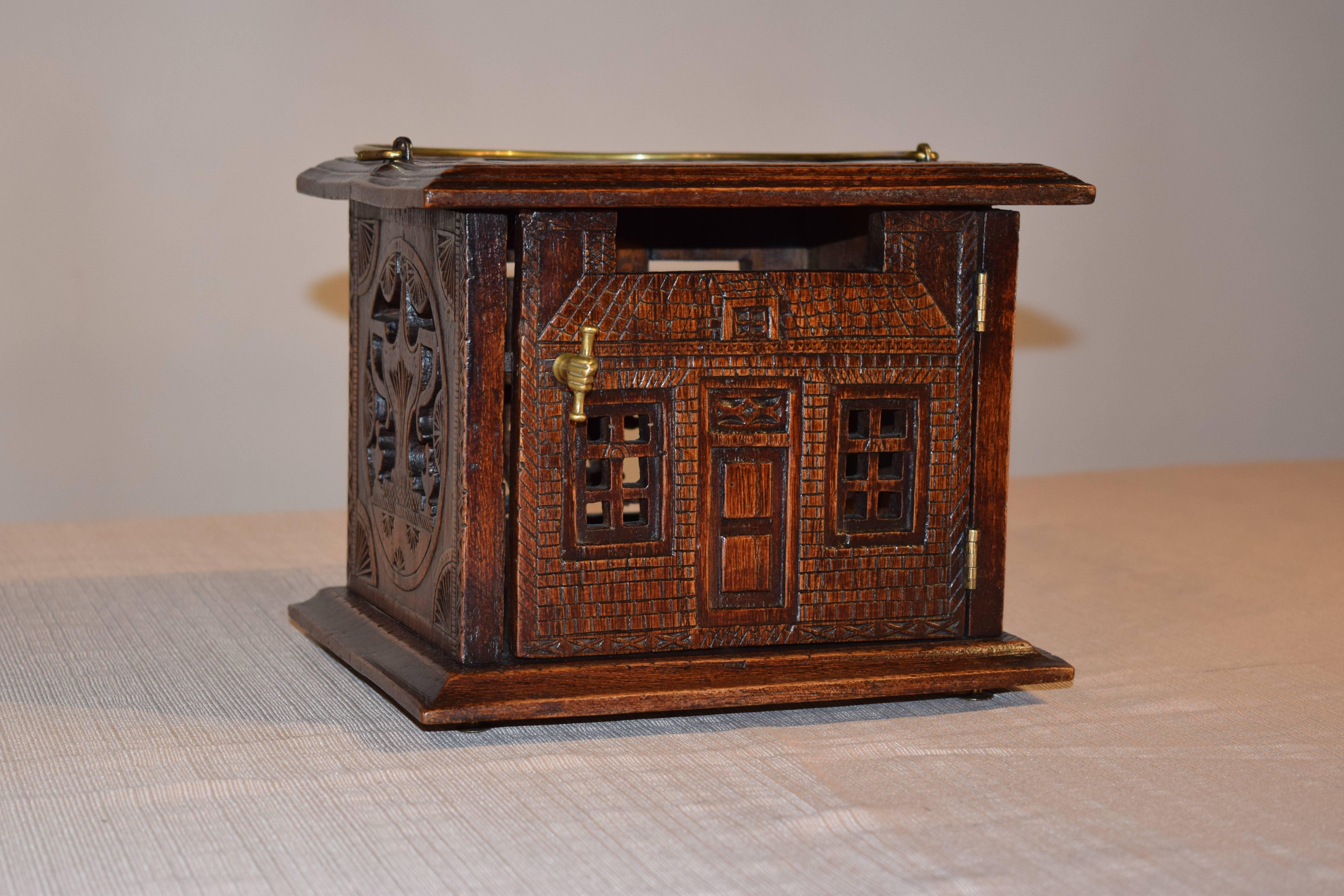 18th century English oak foot warmer with pierced and carved decoration on all sides. The top has a molded edge and is banded with carving surrounding a central pierced medallion. The front looks like a house with a front entrance and hand a scroll