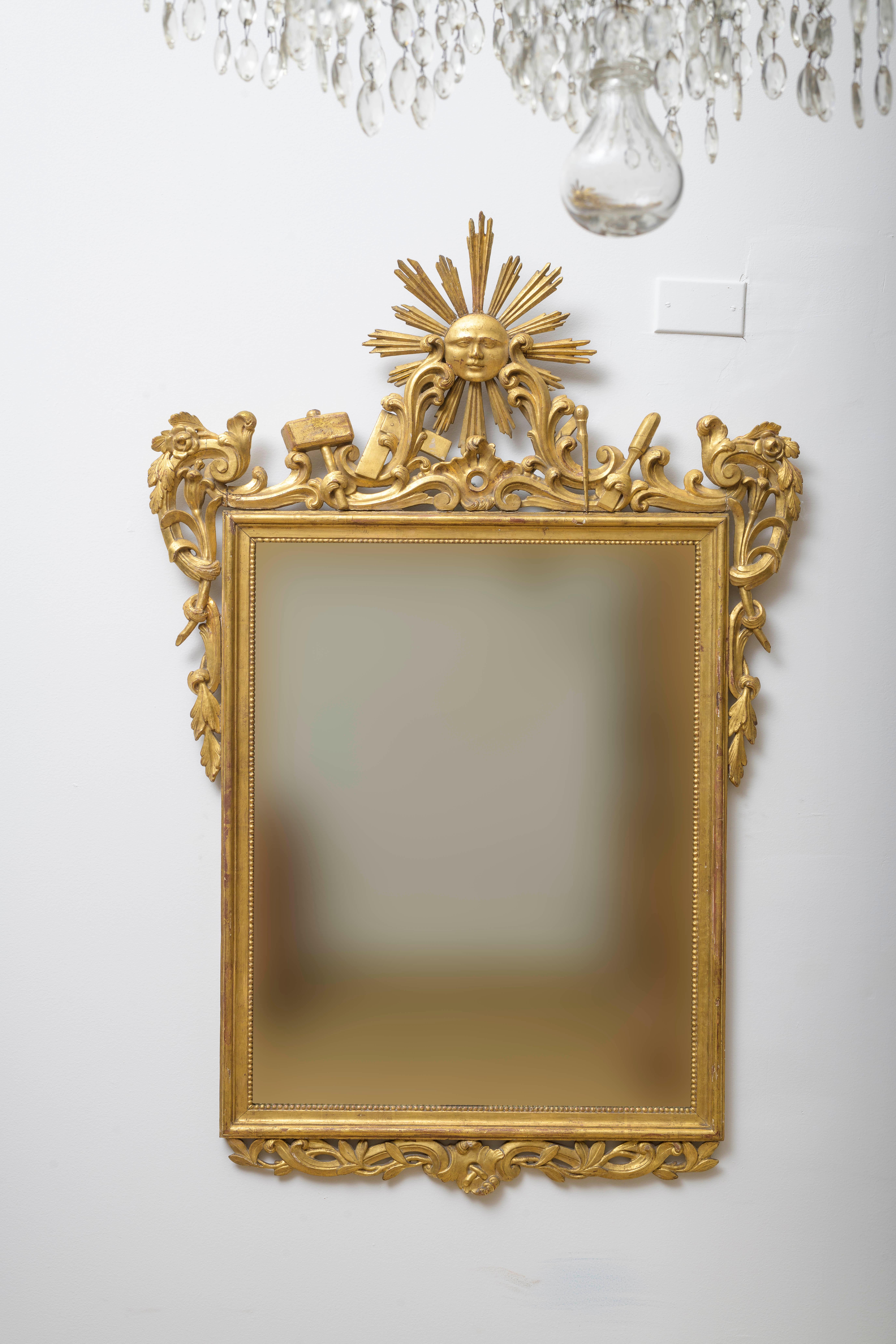 Mitte 18. Jh. Spiegel mit Freimaurersymbolen, Louis XV, durchbrochenes Holz, fein geschnitzt mit Maurerwerkzeugen und mit zentraler Sonnengott-Kartusche, Freimaurersymbolen, Blättern und Zierfries, vergoldet. Spiegelglas, nicht original, aber aus