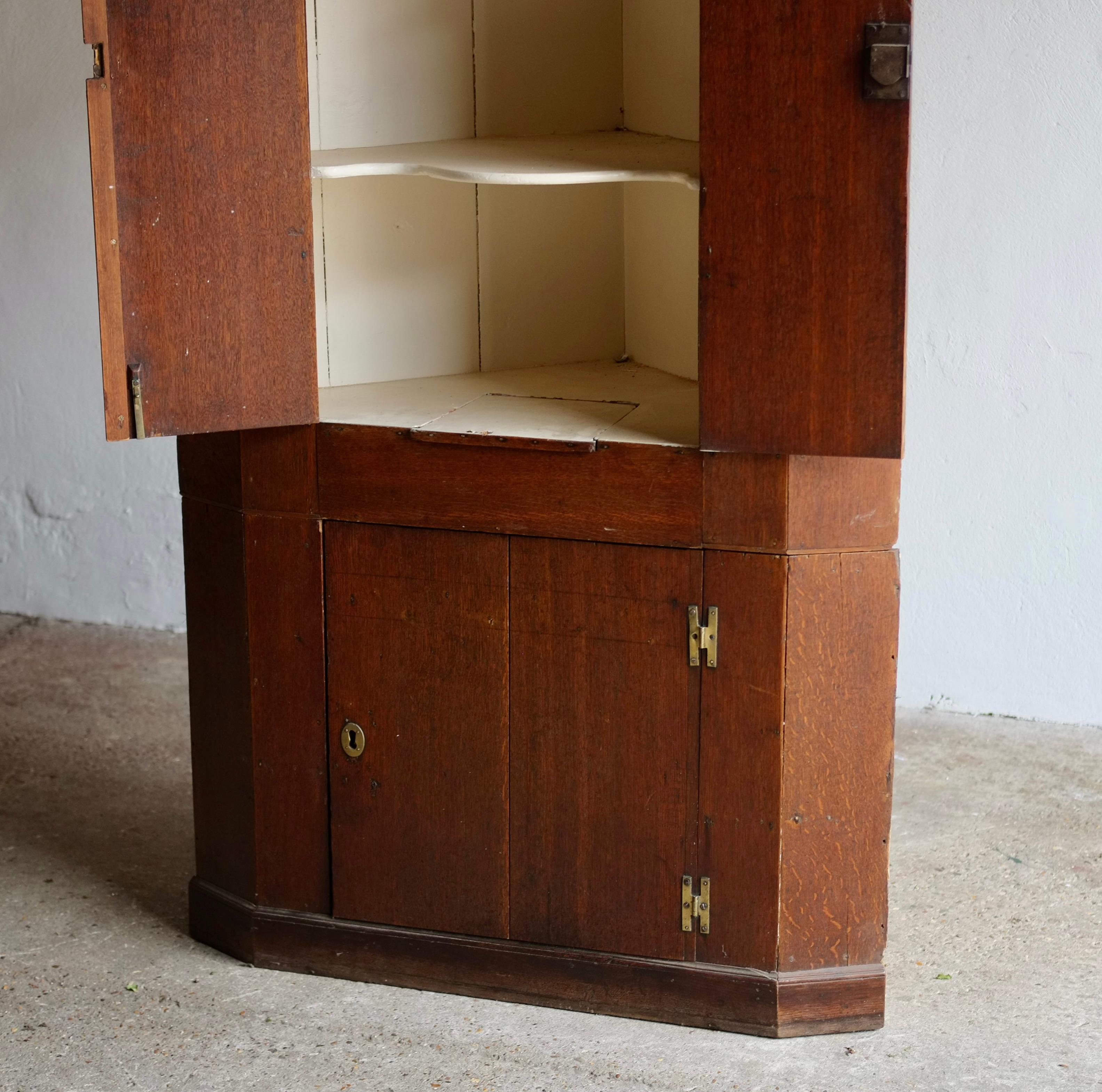 Ein freistehender englischer Eckschrank aus dem 18. Jahrhundert mit gewölbten Türen, charmanten Messingscharnieren und cremefarbener Innenausstattung. 

Der Schrank hat sich im Laufe der Zeit bewährt und ist in einem guten, soliden Zustand. 

Für