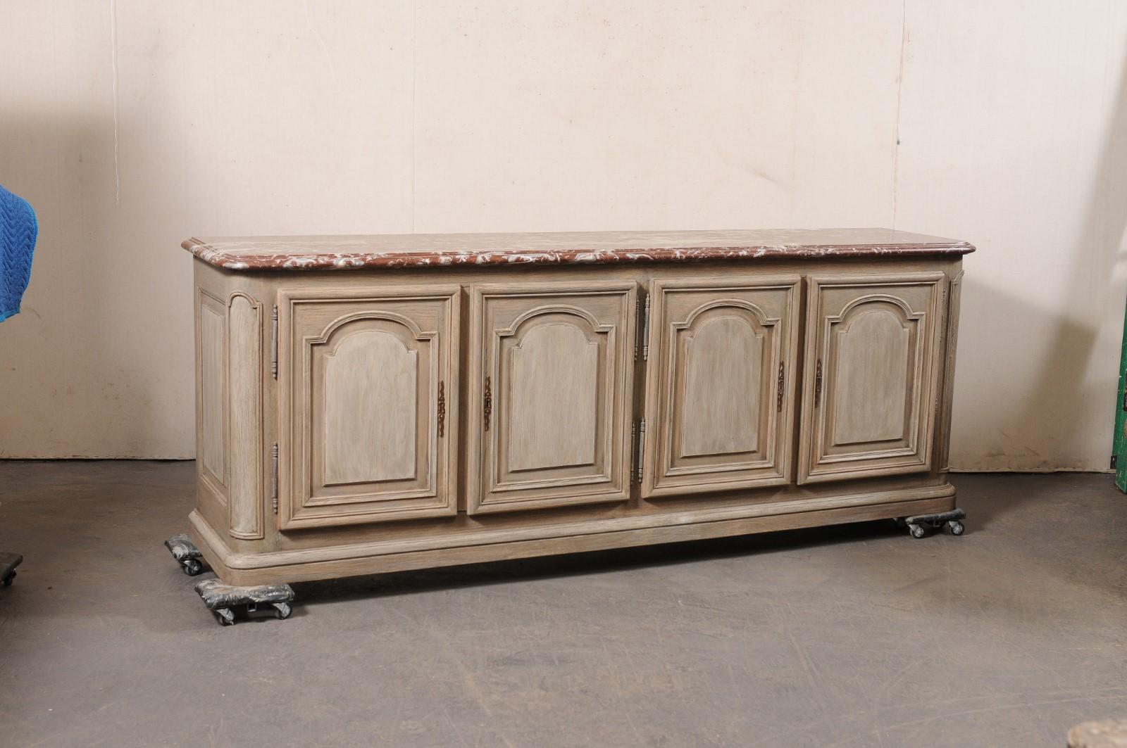 A long French carved and painted wood buffet cabinet with original marble top from the 18th century. This antique sideboard from France, just over 8 feet in length, features a rectangular-shaped top with softly rounded front corners, above a case