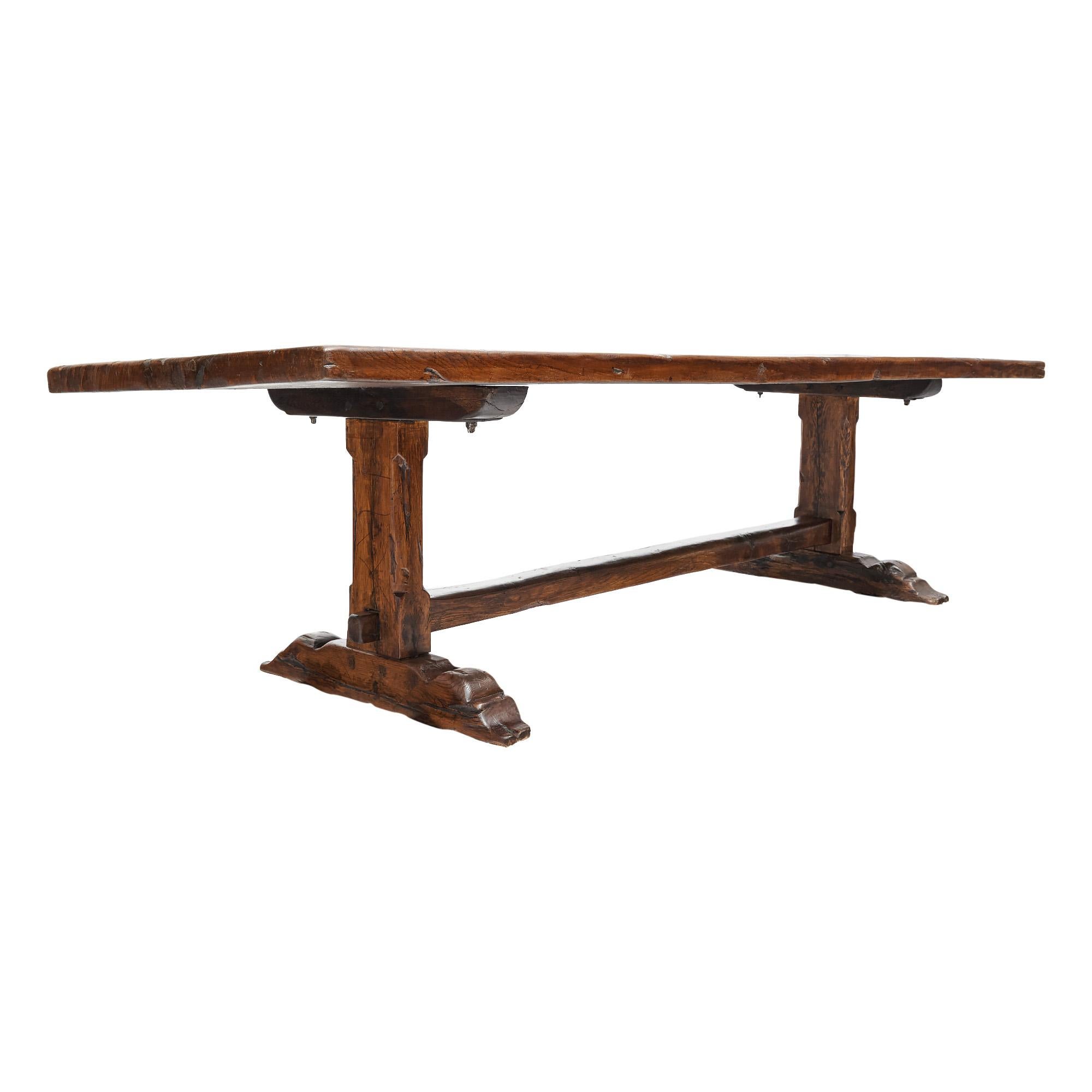 Table de salle à manger française en chêne patiné provenant d'un monastère de la vallée du Rhône, au nord de Lyon, France. Cette table unique est composée d'un plateau en bois massif soutenu par deux piédestaux sculptés à la main, reliés par un