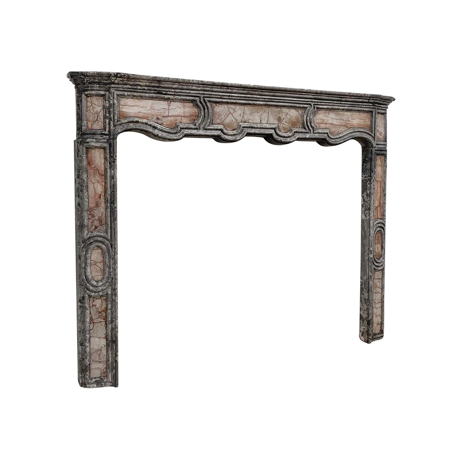 An antique French, XIV slim fireplace mantel made of hand crafted marble, in good condition. The serpentine moulded frieze of the fireplace surround is supported by two detailed carved panelled jambs. Wear consistent with age and use. Circa 1740 -