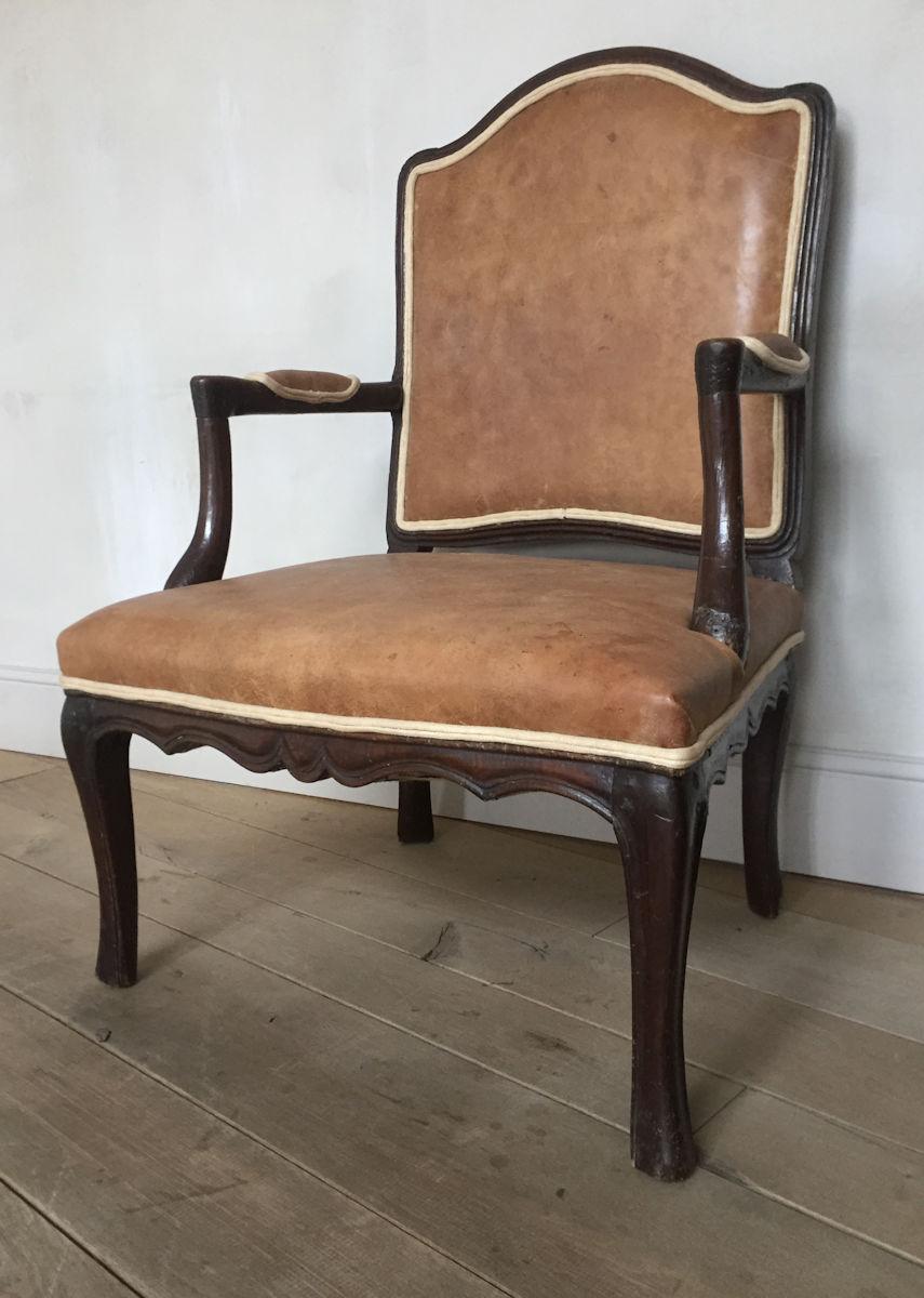 A 18th century Louis XV walnut armchair with 19th century leather upholstery. This chair has the typical Rococo design of the Louis XV era. A period when designers where inspired by natural fluent lines, comfort and joie de vivre. All tough much of