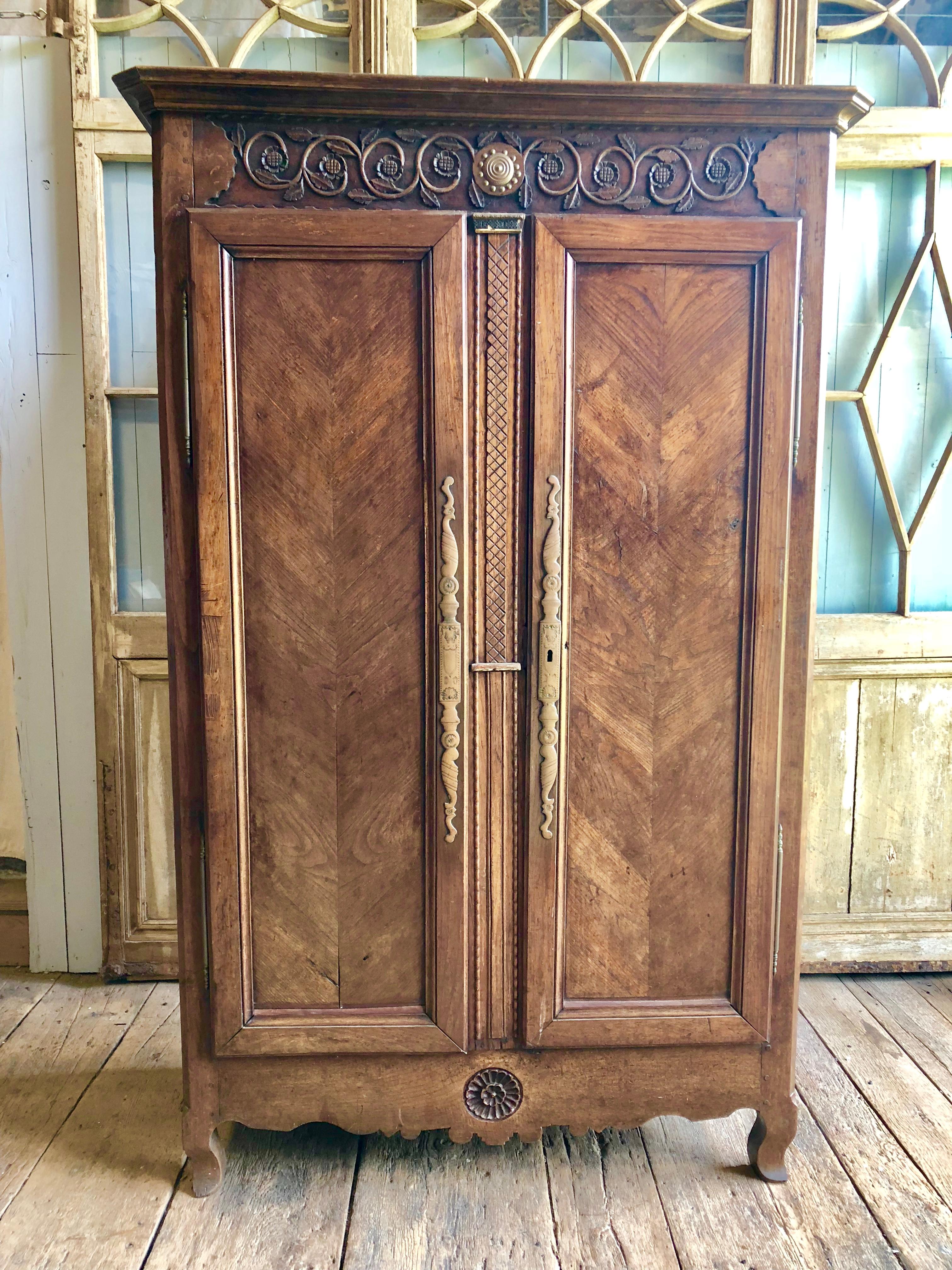 A French Provincial (probably Bresse) Louis XV armoire in elm, with nicely carved upper and lower panels, 2 chevron-paneled full length doors on short cabriole feet, circa 1780. The painted interior has removable shelves.