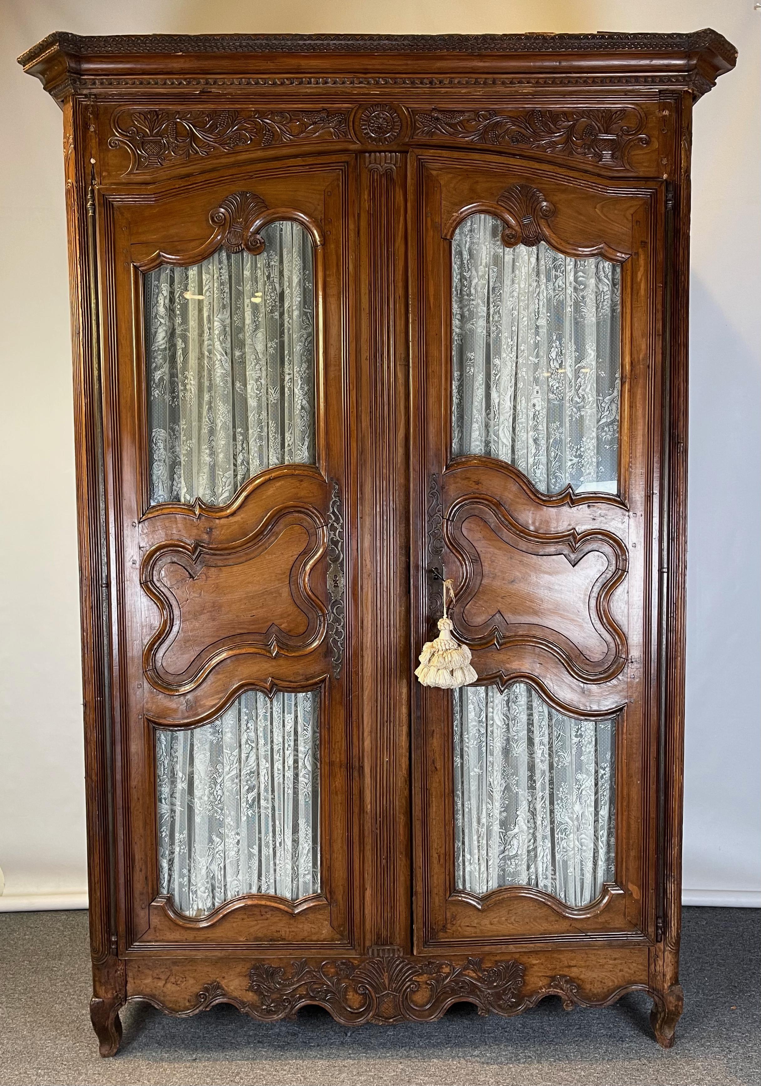 A exceptionally large and intricately carved late 18th C. French fruitwood armoire. The inset glass of the doors is early and most likely original to the piece.