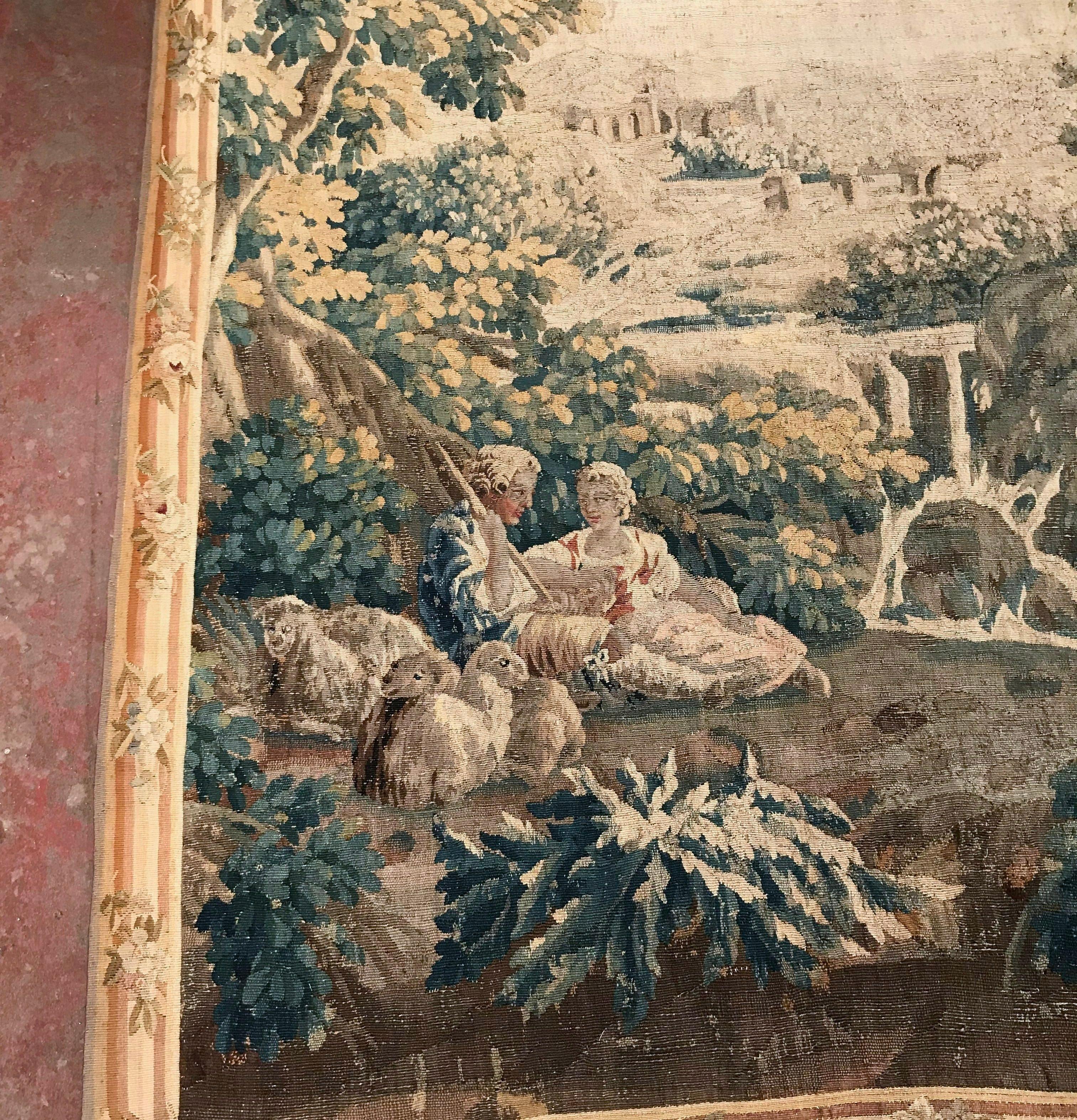 Setzen Sie mit diesem großen antiken Wandteppich aus Frankreich ein Zeichen in Ihrem Zuhause. Dieser um 1750 in Aubusson handgewebte Wandbehang im Boucher-Stil zeigt eine friedliche Hirtenszene, die auf der linken Seite einen jungen Hirten zeigt,