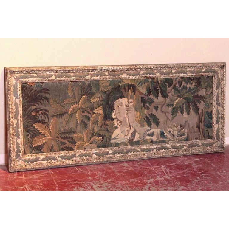 Bring beautiful color to your home with this unique, antique Aubusson tapestry. Woven in France, circa 1760, the elegant tapestry features a young woman holding a torch with verdure and foliage surrounding her. The tapestry is set inside an old