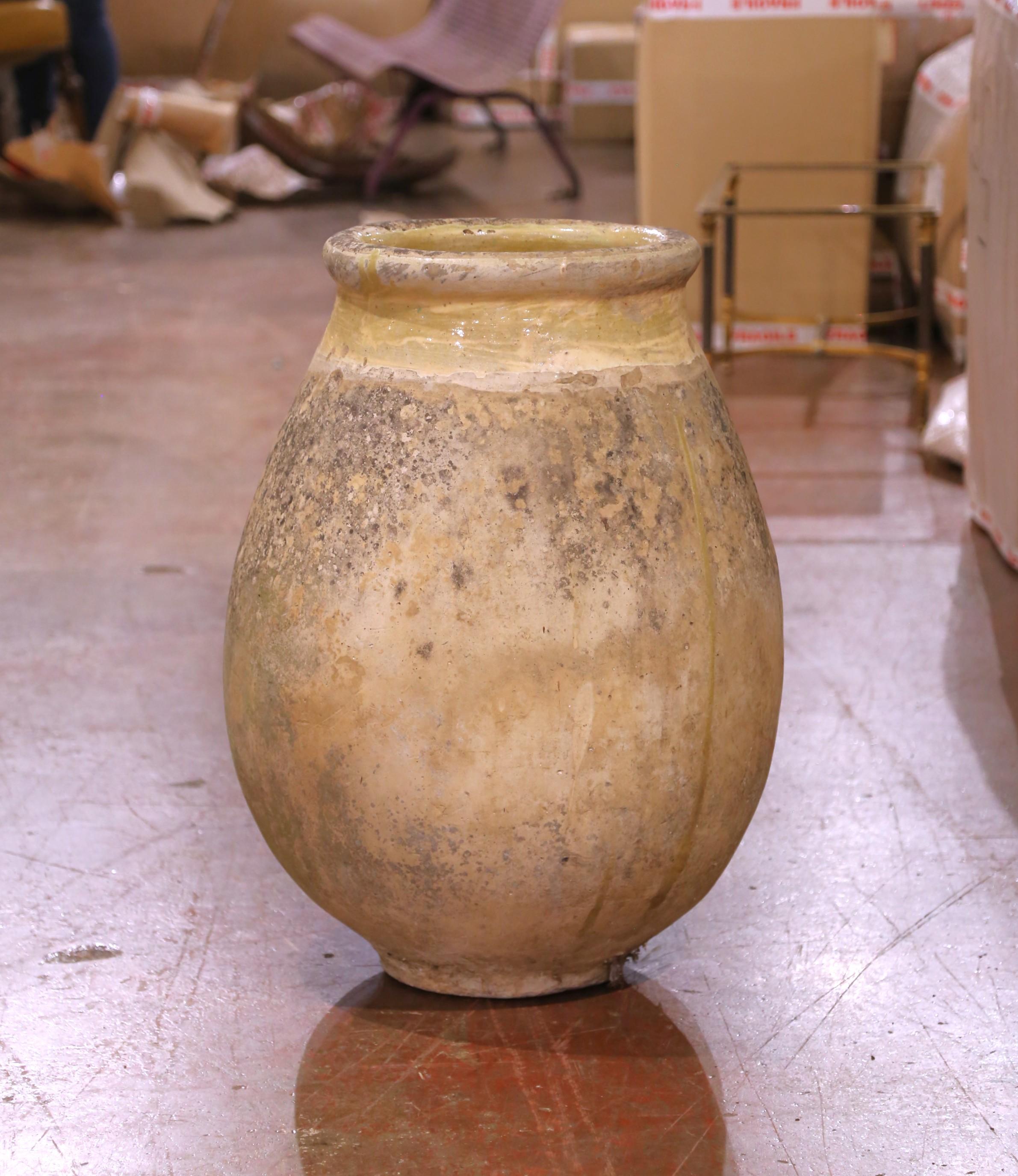 Dieser große antike Olivenölkrug wurde um 1780 in Biot in der Provence hergestellt. Das aus blondem Ton gefertigte Gefäß in der für die Region charakteristischen runden Form hat einen breiten, bauchigen Körper und einen gerollten Hals. Der obere