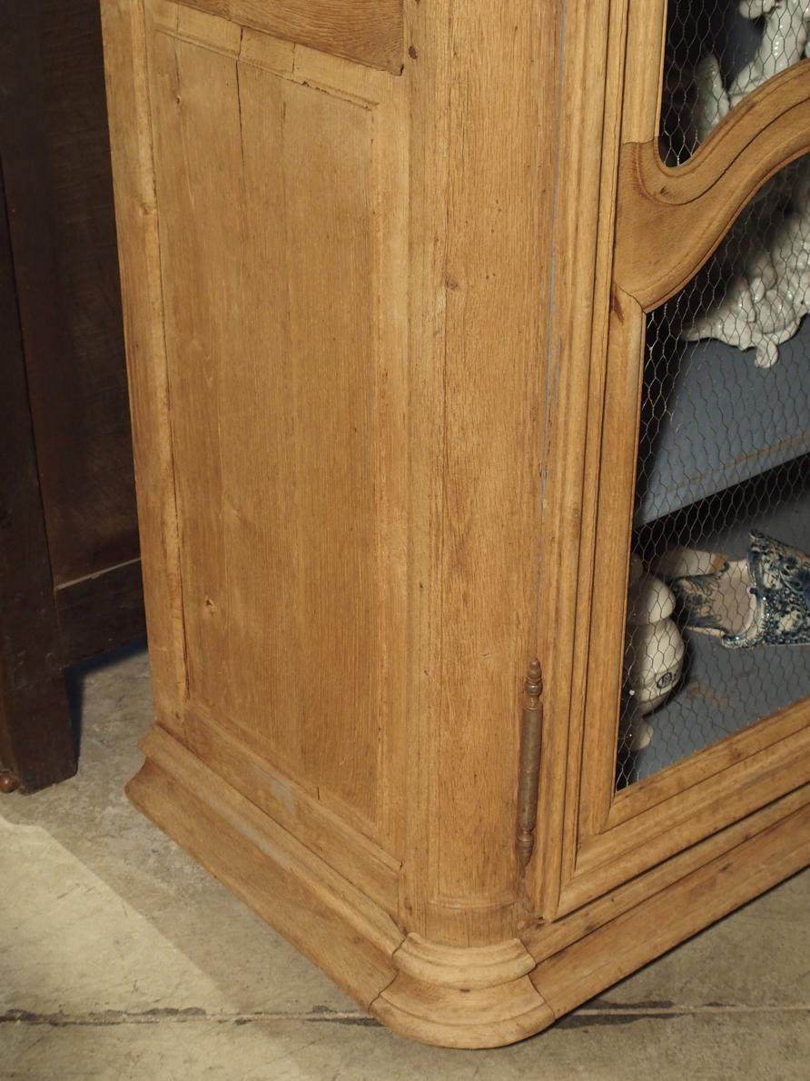 This handsome French oak bibliotheque, or wooden bookcase, dates to the middle of the 1700s. The oak has been stripped and bleached, and interior painted with a French blue lavender. Originally, an Armoire de boiseries, it’s feet are hidden beneath