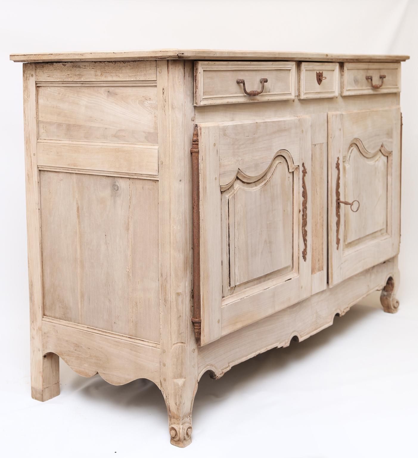 Credenza a buffet, in noce sbiancato, in stile provenzale, con piano rettangolare modanato, sopra grembiule a tre cassetti, ante a doppio armadio aperte su cerniere di ferro, grembiule sagomato sollevato su gambe cabriole, che terminano in punte di