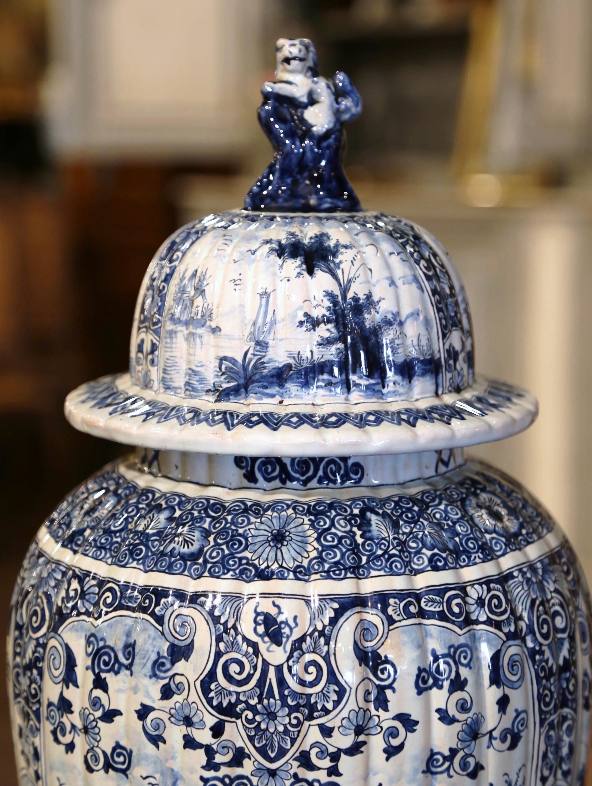 This important antique vase was crafted in France, circa 1780. Round in shape with gadrooned body style, the elegant potiche features hand painted decor of figural medallions divided with high relief leaf and shell motifs; each painted medallion