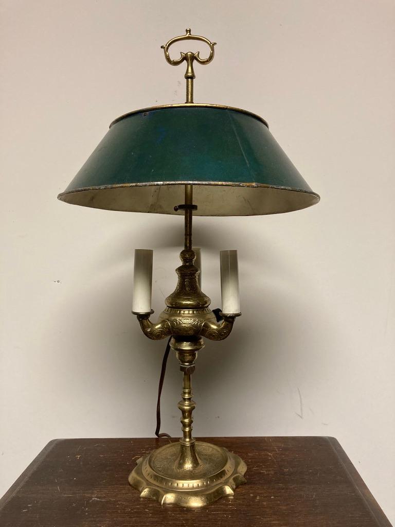 A 19th century French Empire etched brass bouillotte lamp, originally and oil lamp that has been electrified. With three arms below a green painted adjustable tole shade, the body and base incised with floral designs. This is a sweet little lamp of