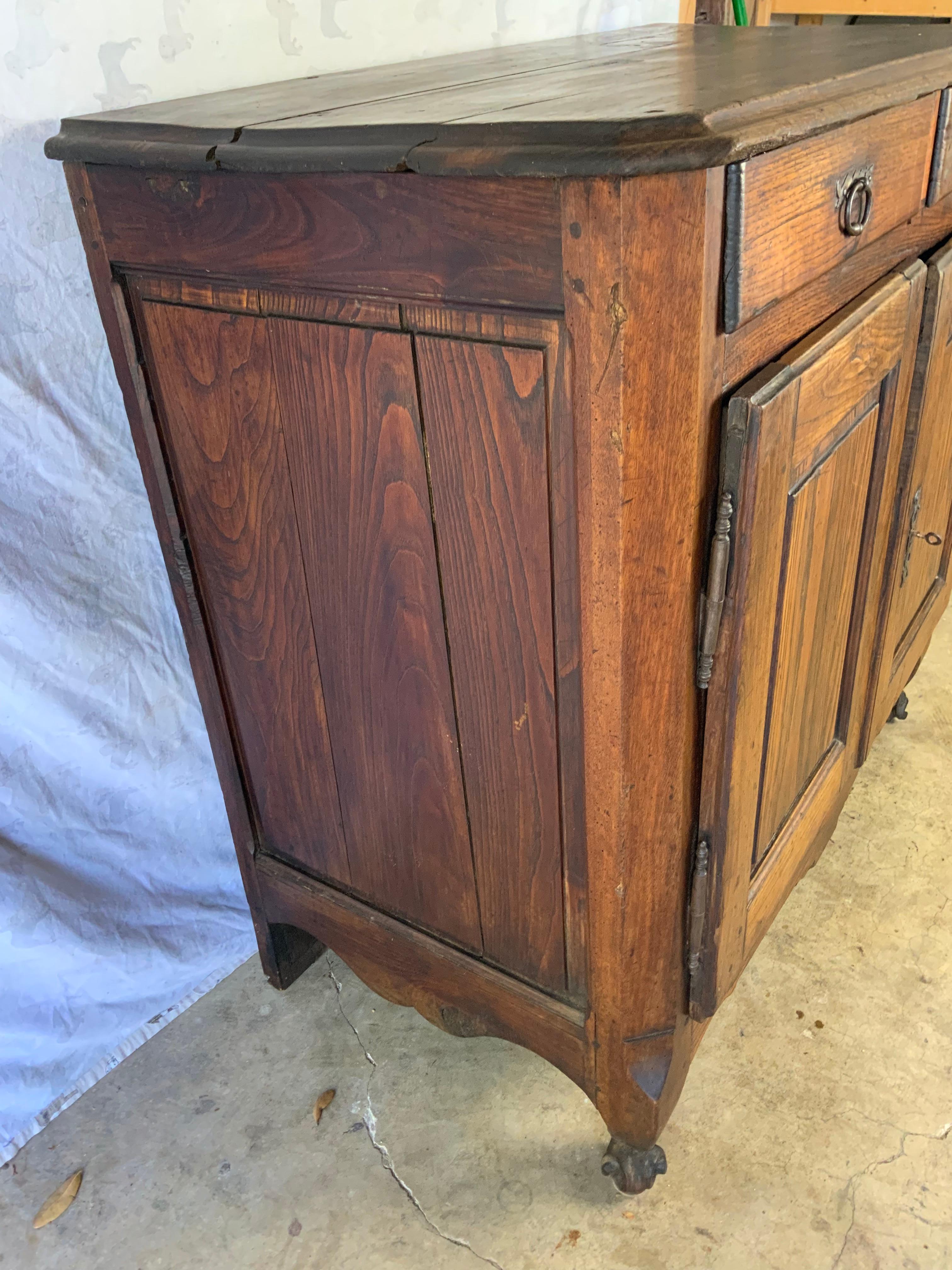 18th century Oak French Buffet in original surface. Raised panel sides and doors with the original working lock and key. One large original storage shelf in the bottom cupboard area. This was a well used utilitarian piece of furniture which retains