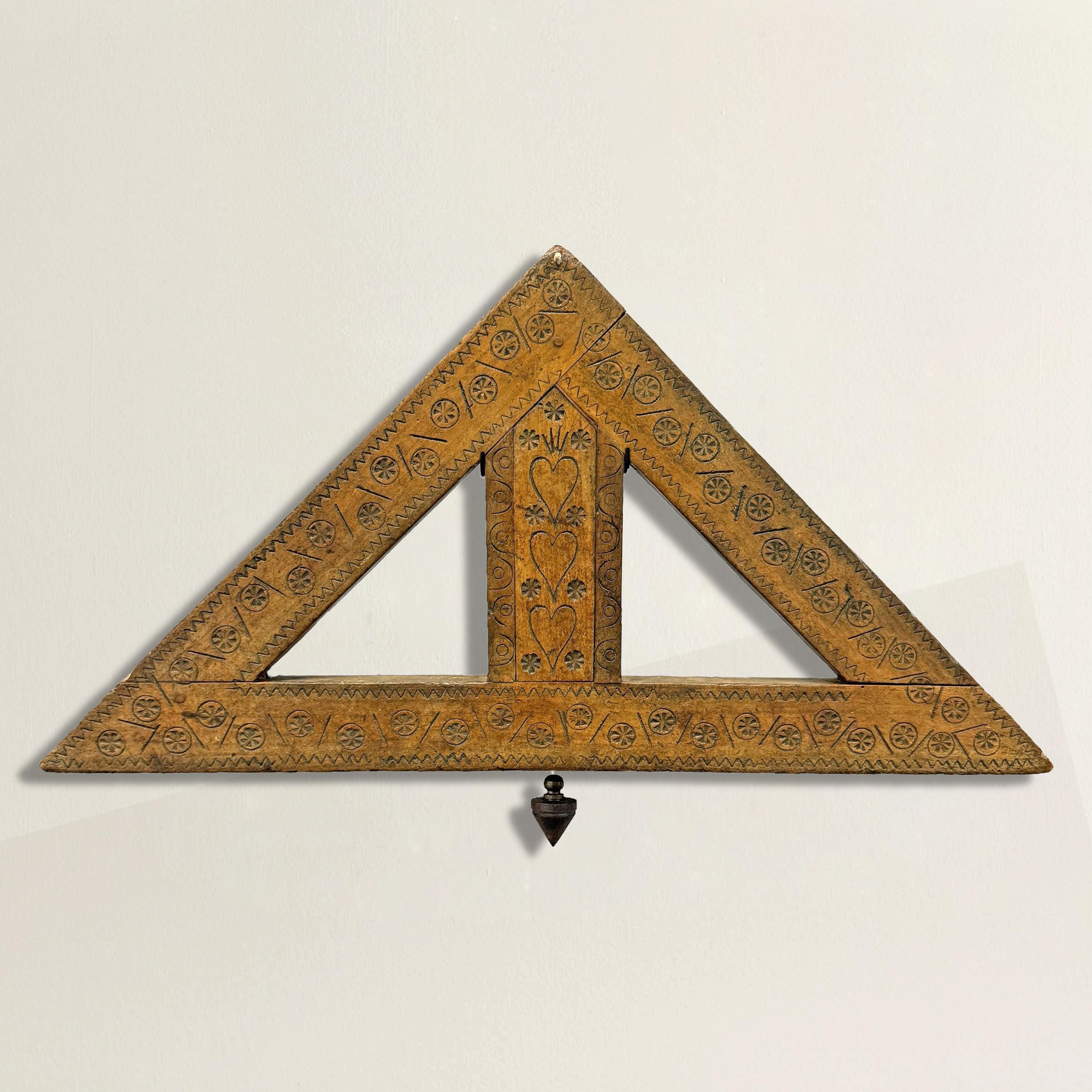 This exquisite 18th-century French builder's square with plumb bob is a remarkable piece of craftsmanship and history. Carved from fine maple wood, it features intricate decorations of incised and stamped hearts and stylized flowers, reflecting the