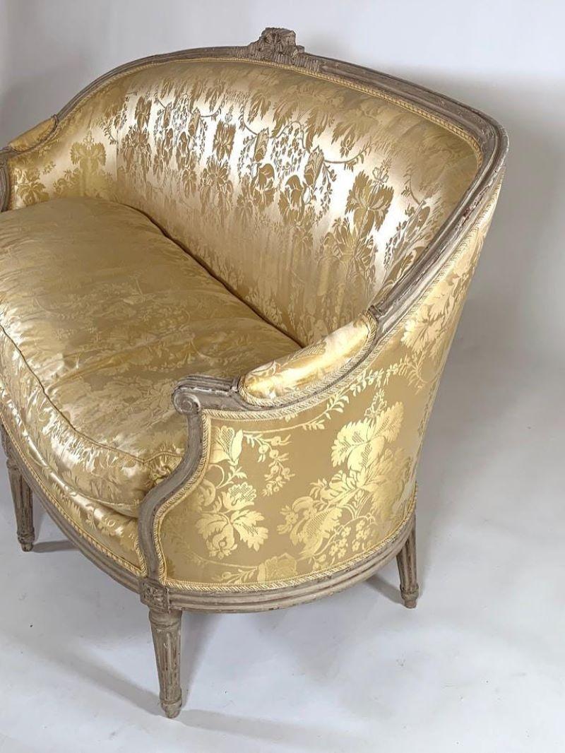 A fine Louis XVI gray painted canape, 18th century, circa 1790, with ribbon carved cresting over upholstered back and scrolled padded arms and seat, raised on tapering fluted legs. Upholstered in Scalamandre yellow silk damask.