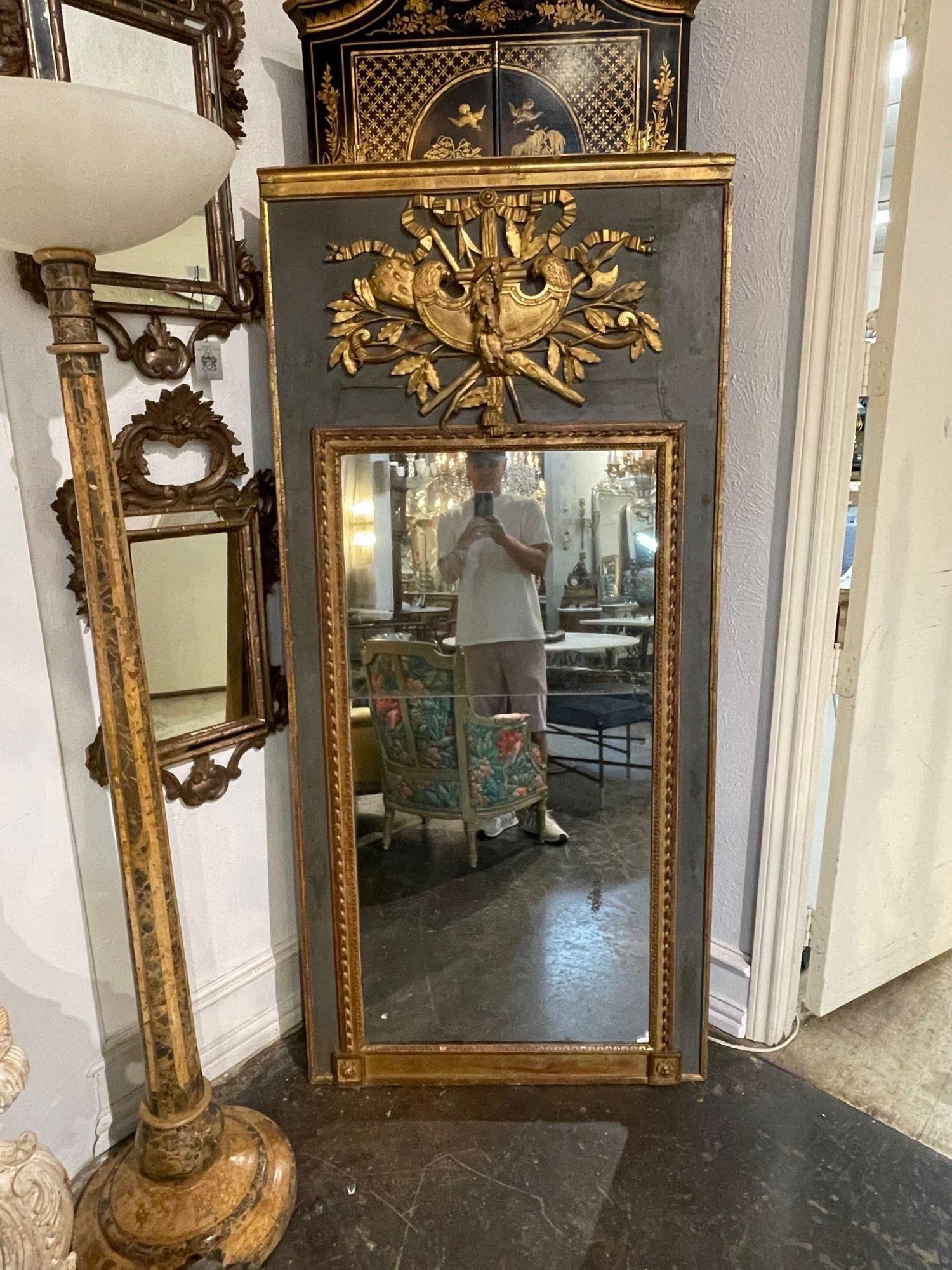 Magnifique miroir Trumeau du 18ème siècle, sculpté et doré à la feuille. Très belles sculptures, dont un grand écusson au sommet du miroir. Belle patine grise/verte également. Fabuleux !