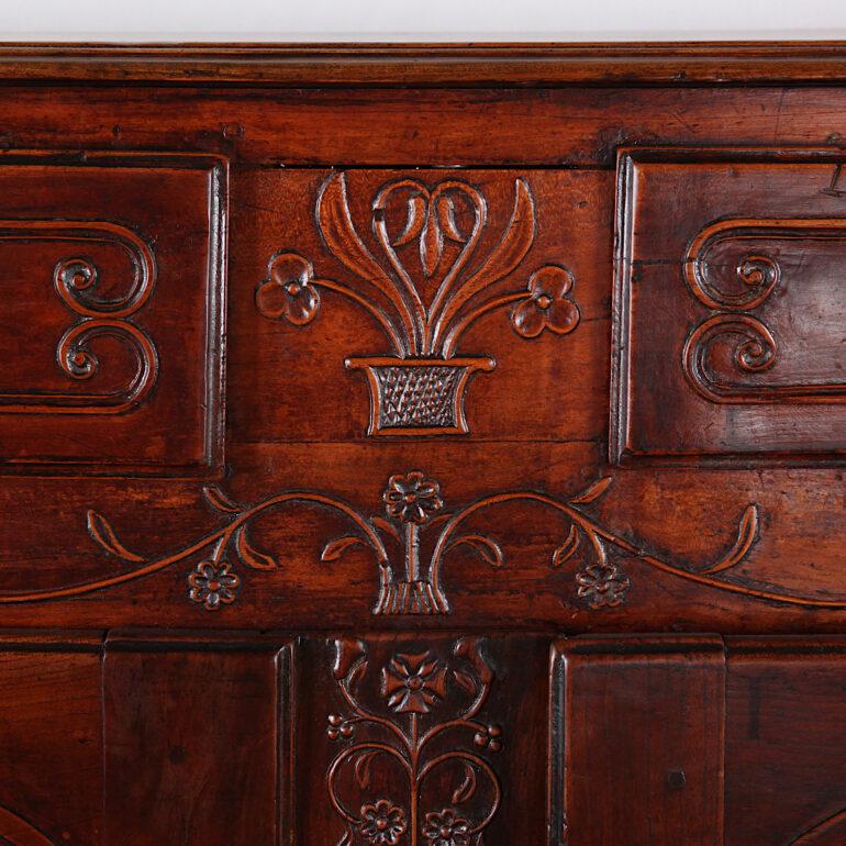 A French carved cherry buffet having a pair of shaped-paneled doors opening to a cupboard with single shelf, and with a pair of upper drawers. Cabriole legs with scrolled feet joined by a scalloped apron with central carved details. Further carved