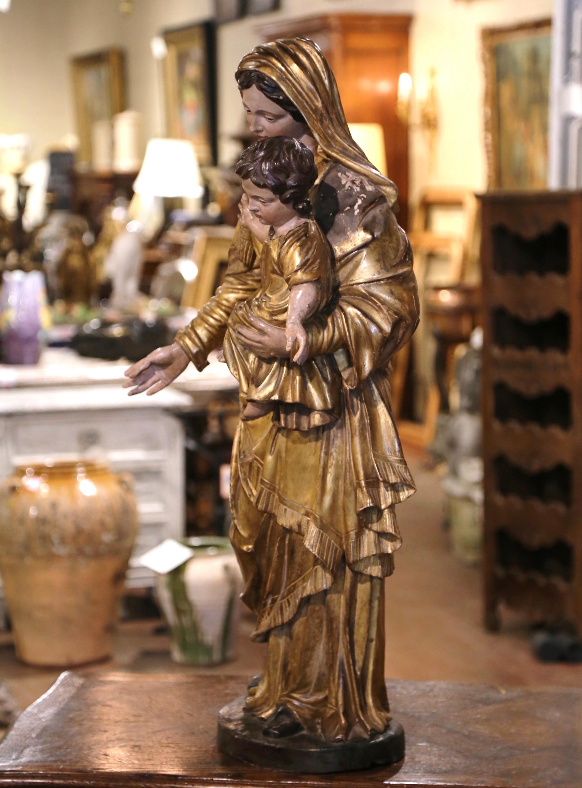 Hand carved circa 1780, this important antique statue of the Virgin Mary and her Son was found in a chapel in Southern France. The large alluring polychrome and gilt sculpture in high relief, features Madonna carrying our Lord Jesus Christ with His