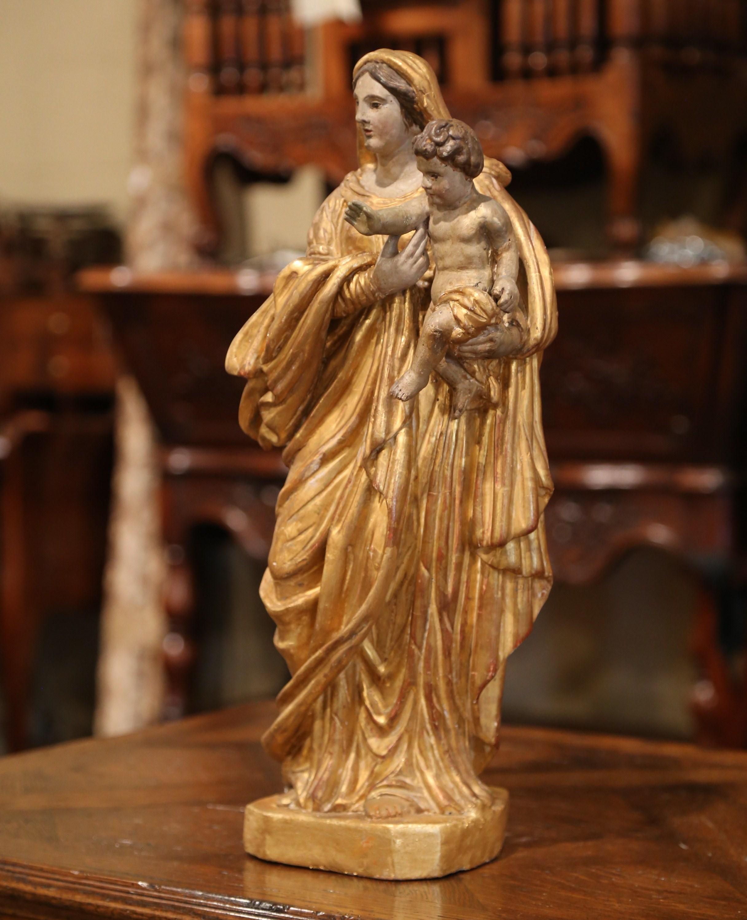 This elegant antique statue of the Virgin Mary and her Son, found in a chapel, was carved in Southern France, circa 1780. The large alluring polychrome and gilt sculpture in high relief, features Madonna carrying our Lord Jesus Christ with His right