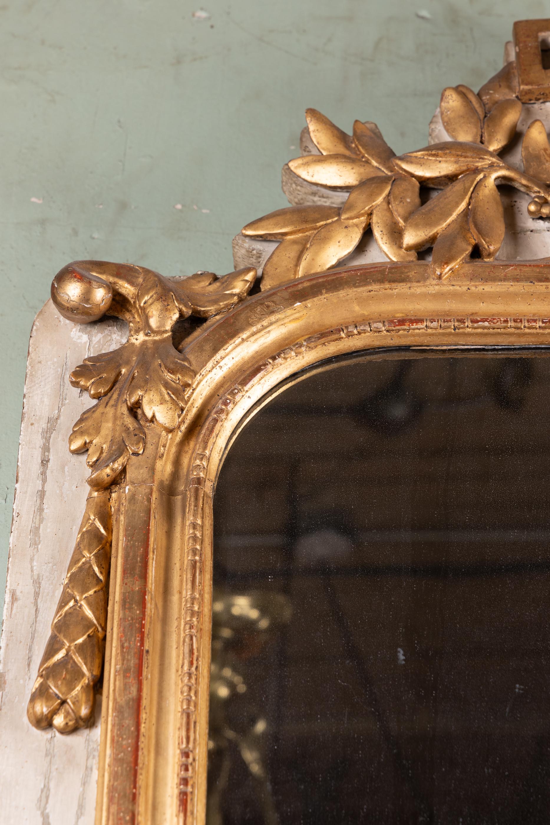 Specchio francese del XVIII secolo Luigi XVI intagliato, foglia d'oro e dipinto di bianco con motivo a foglie, disegno floriato nella parte inferiore, sormontato da un'urna greca con fiamma.

Questo pezzo è una collezione di un'azienda familiare di