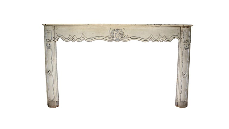 A French painted oak fireplace in the manner of Louis XV, 18th century. The shaped panelled frieze and jambs surmounted by a serpentine shaped shelf.