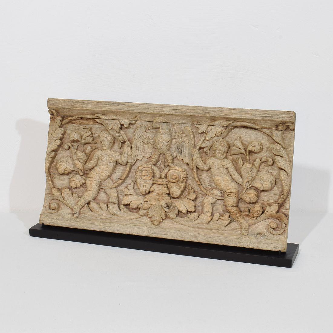 Magnifique panneau en chêne patiné représentant deux anges baroques et un aigle debout sur des têtes de béliers.
Les intempéries et les petites pertes indiquent qu'il faisait probablement partie d'un panneau plus grand.
France vers 1750. Traité