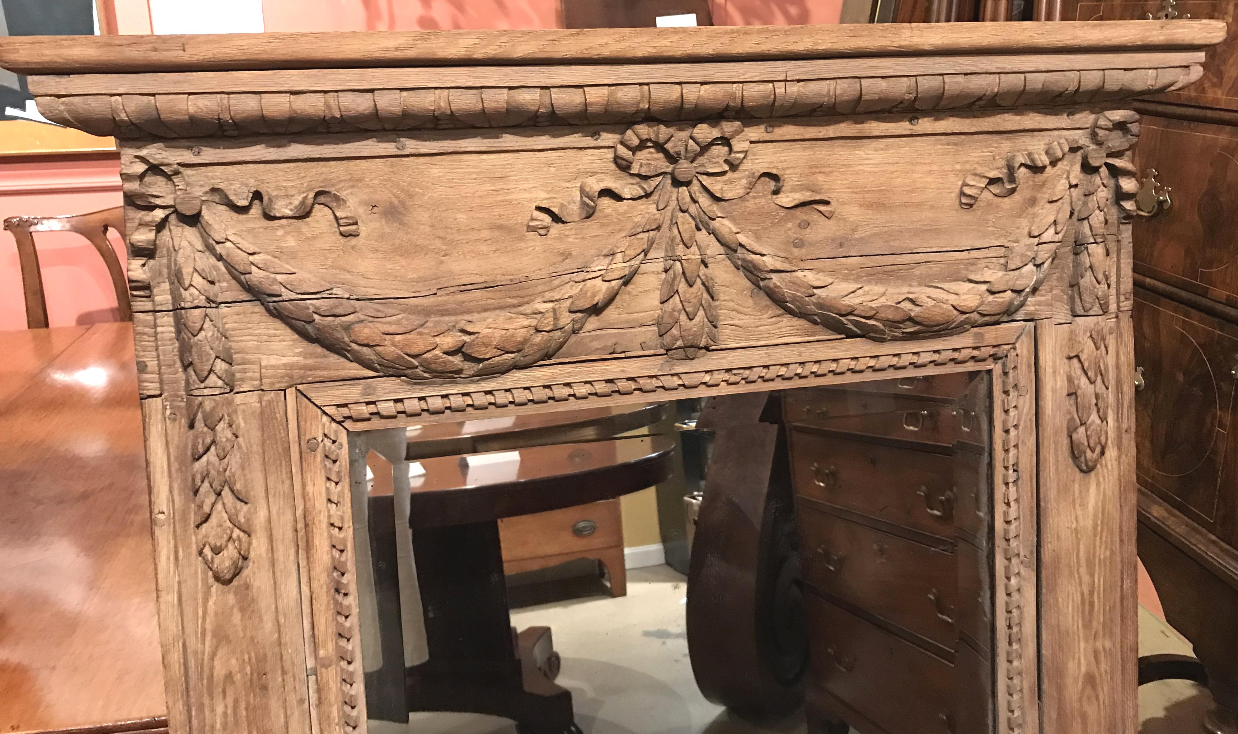 A fine French oak wall mirror with carved cornice surmounting a carved double swag with ribbon decoration over the mirror, with a rope carved border and foliate decorations on the surround, all with pegged construction. Very good overall condition,