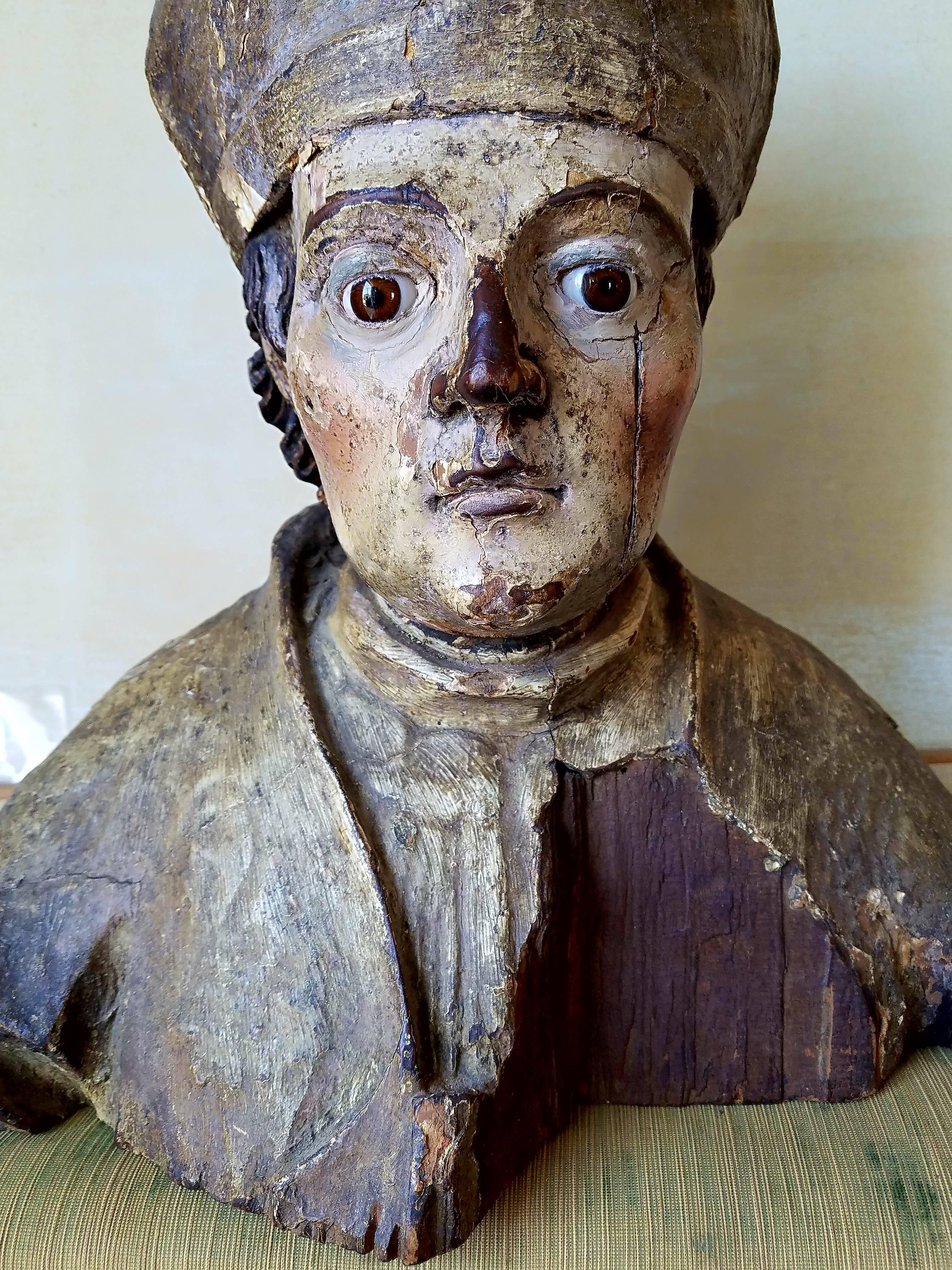 A very finely articulated carved French Bishop statue with very realistic glass eyes and painted face, cloak and hat. Wonderful patina and wear with deeply carved ears, hair and facial features. Paint is well kept with beautiful craquelure. Most