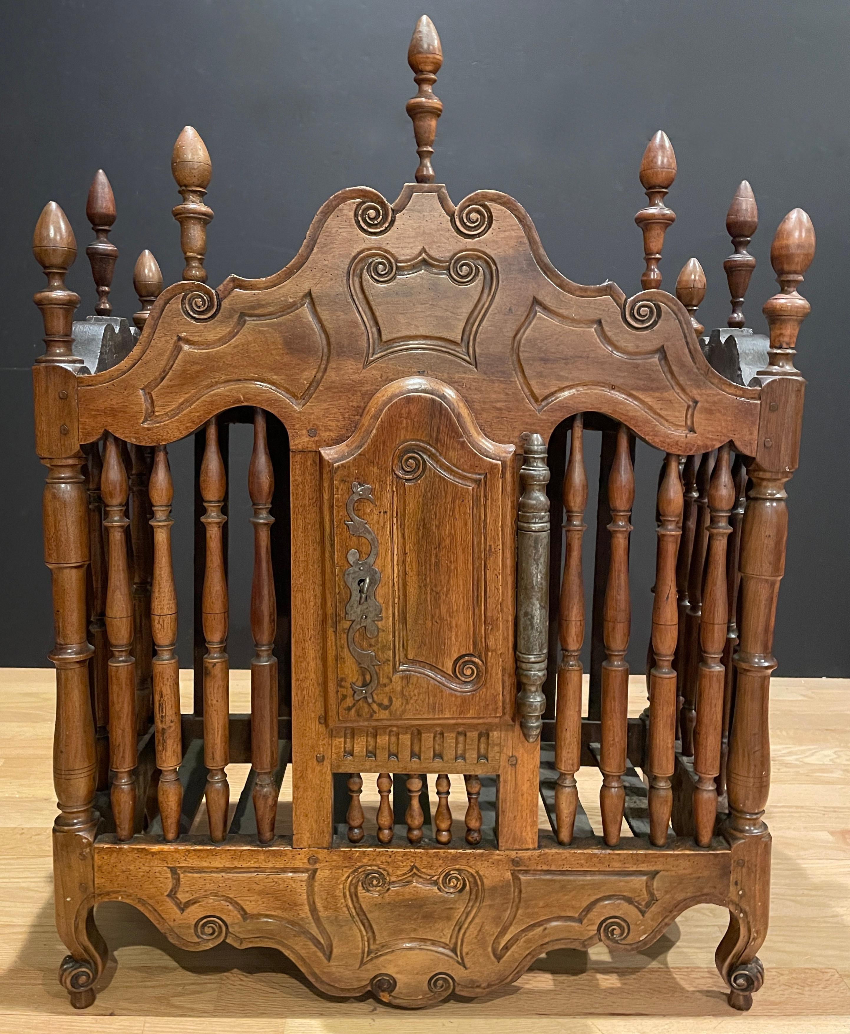 An antique 18th Century French Provincial panetiere, bread safe. Walnut with iron hardware. Features decorative carvings to cornice, door & apron, turned spindles and decorative finials. Center door has working lock with one included key.