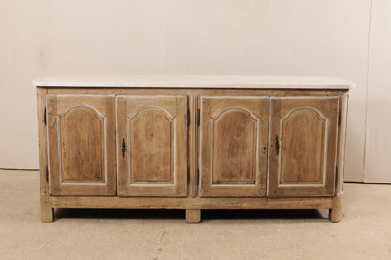 An 18th century French marble-top buffet cabinet. This antique cabinet from France, which is approximately 7.5 feet in length, features a newer addition of a honed marble top which rests above two pair of arched panel doors, carved and rounded front